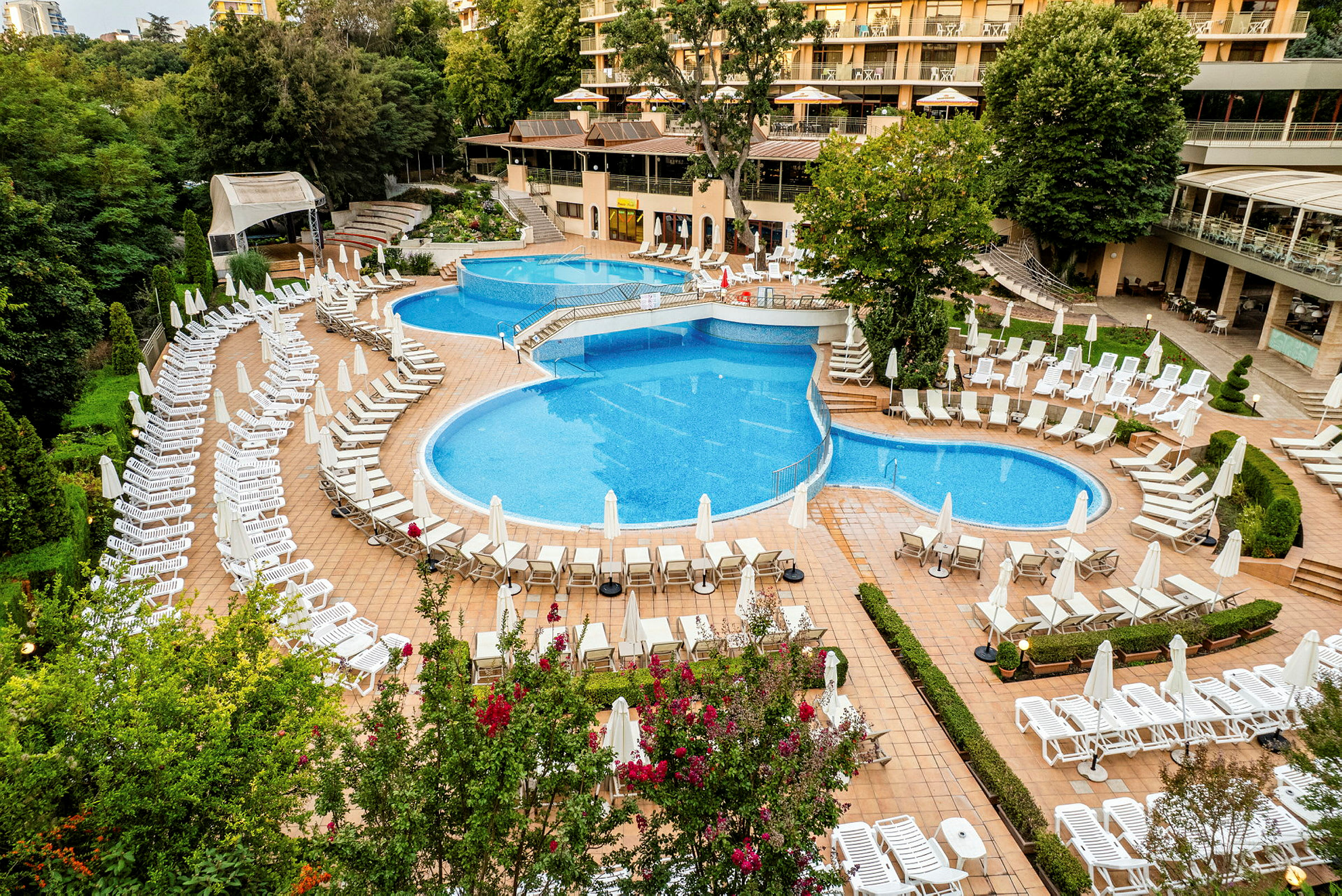 Bild av ett hotellområde med flera swimmingpooler och solstolar. (AI-genererad text)
