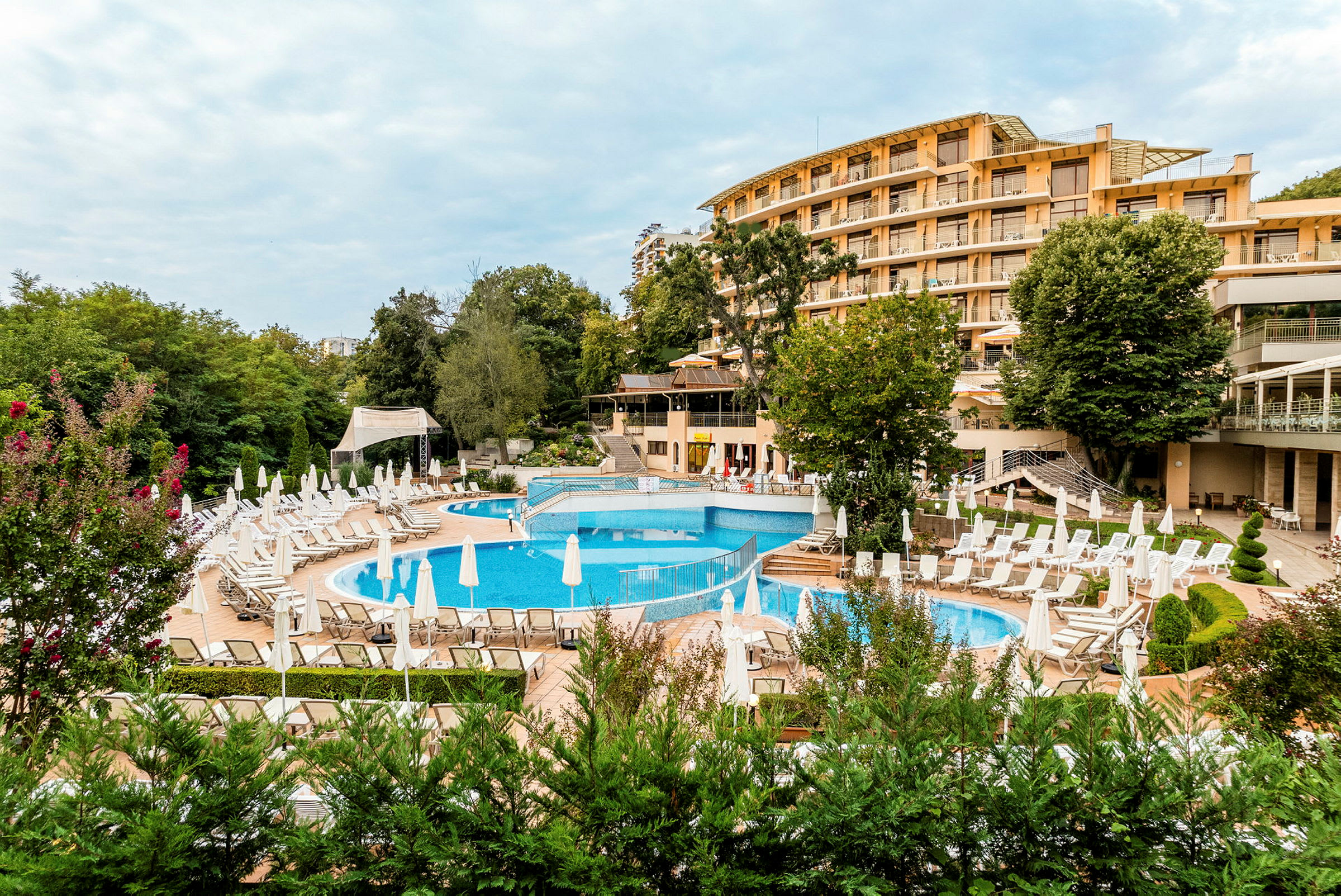 Hotellbyggnad med poolområde och solstolar. (AI-genererad text)