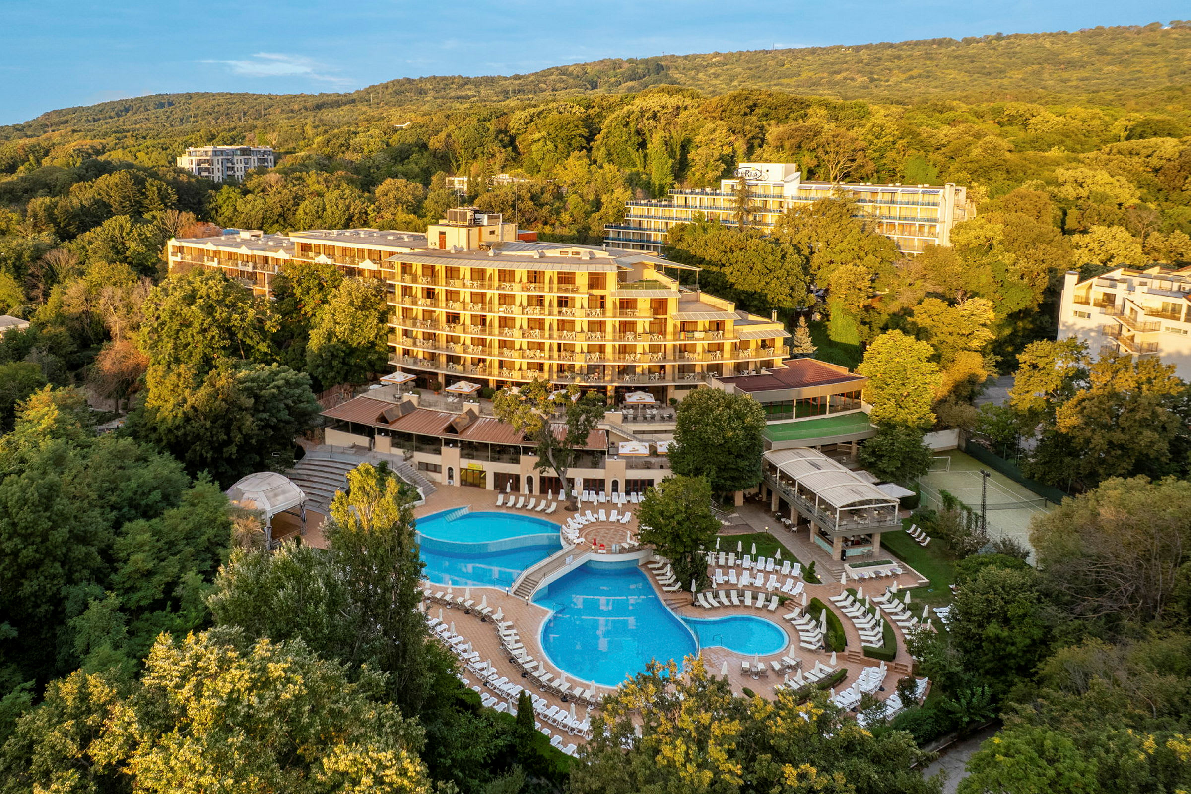 Hotellbyggnad omgiven av grönska med en stor poolområde. (AI-genererad text)