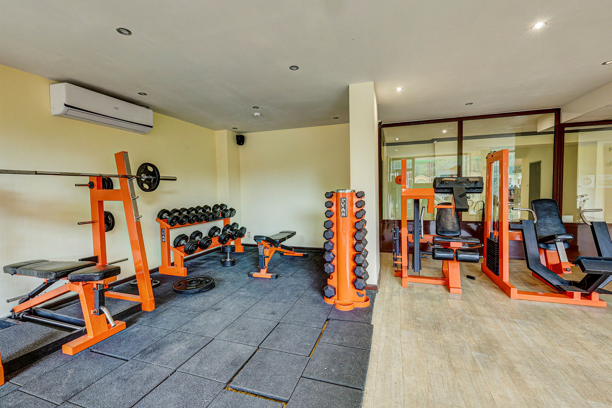 Ett gym med träningsutrustning såsom skivstång, hantlar och maskiner för styrketräning. Ljusa väggar och golv. (AI-genererad text)