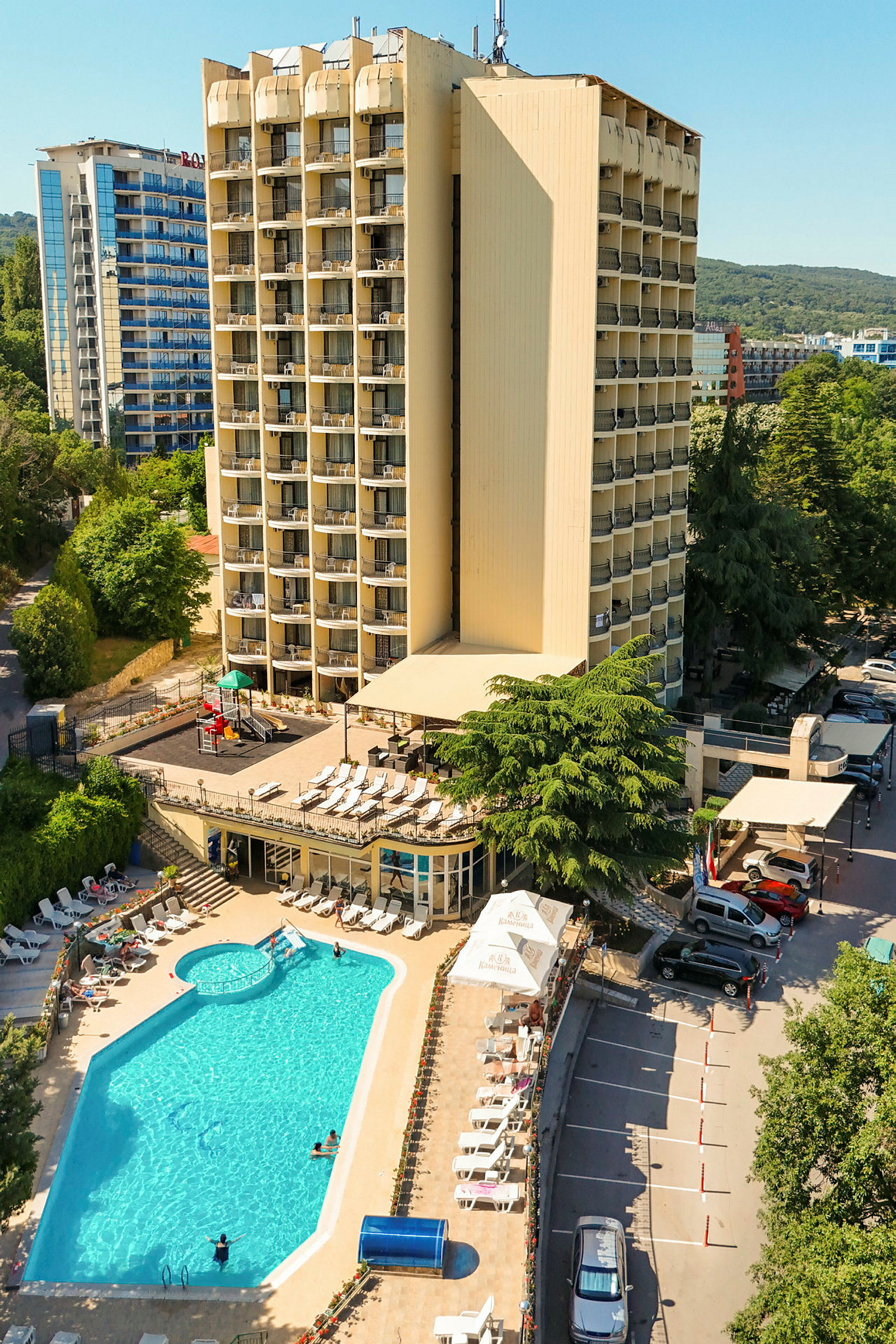 Ett hotell med en stor pool, solstolar och parkeringsplatser. (AI-genererad text)