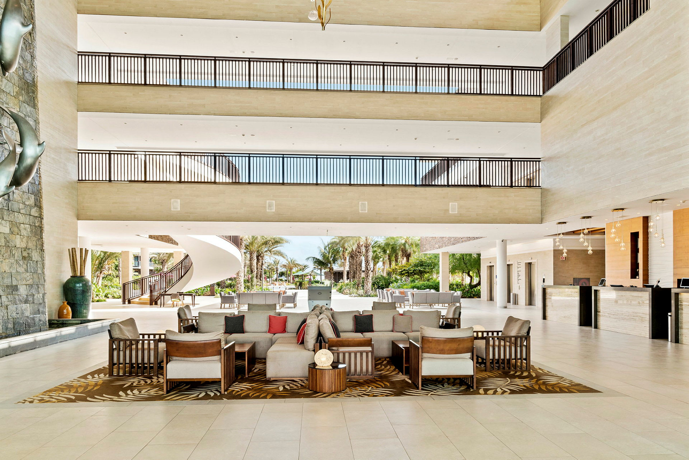 En rymlig hotellobby med sittplatser, trappa och reception. (AI-genererad text)
