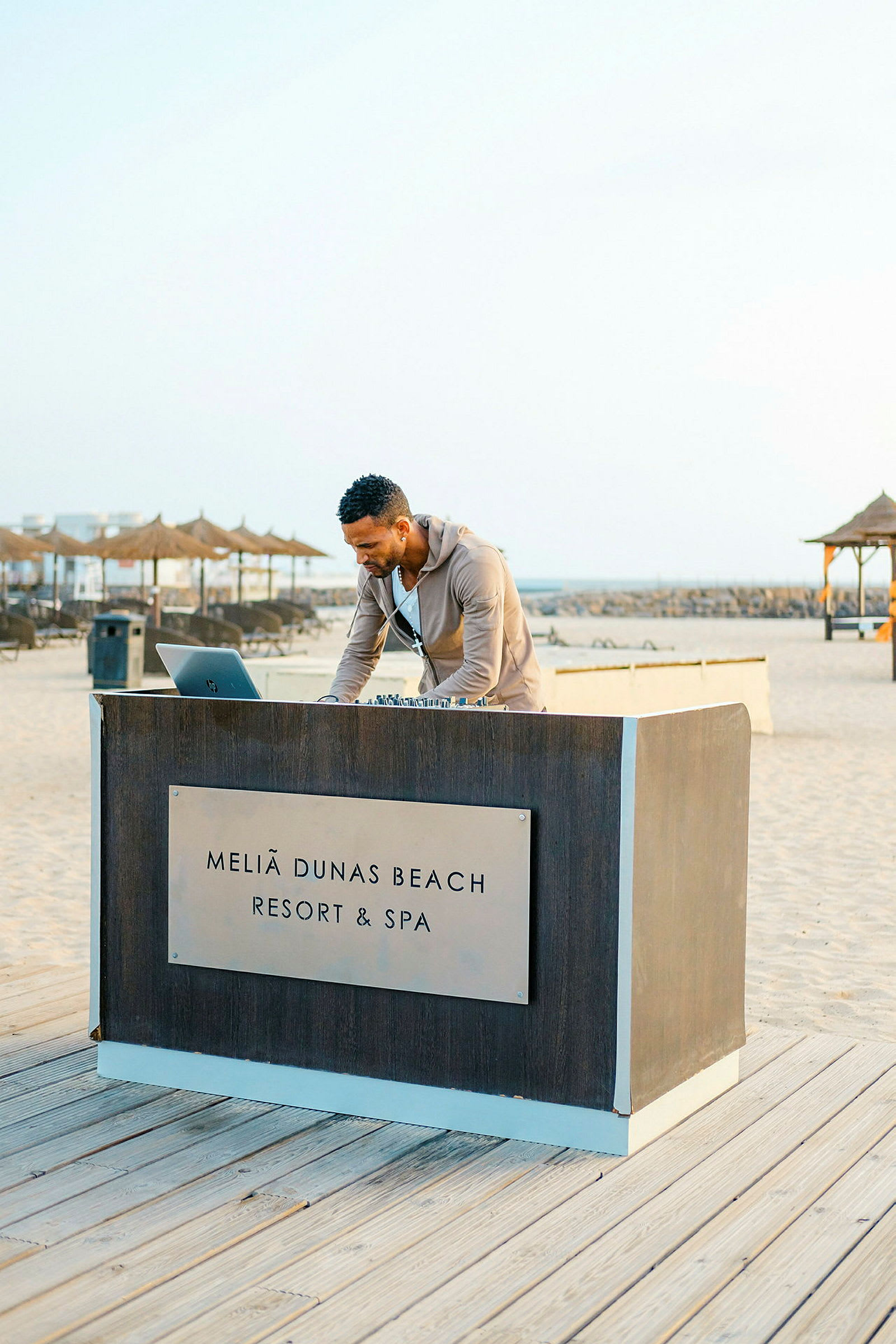 En person står vid ett bord med texten 'Meliã Dunas Beach Resort & Spa' vid stranden. (AI-genererad text)
