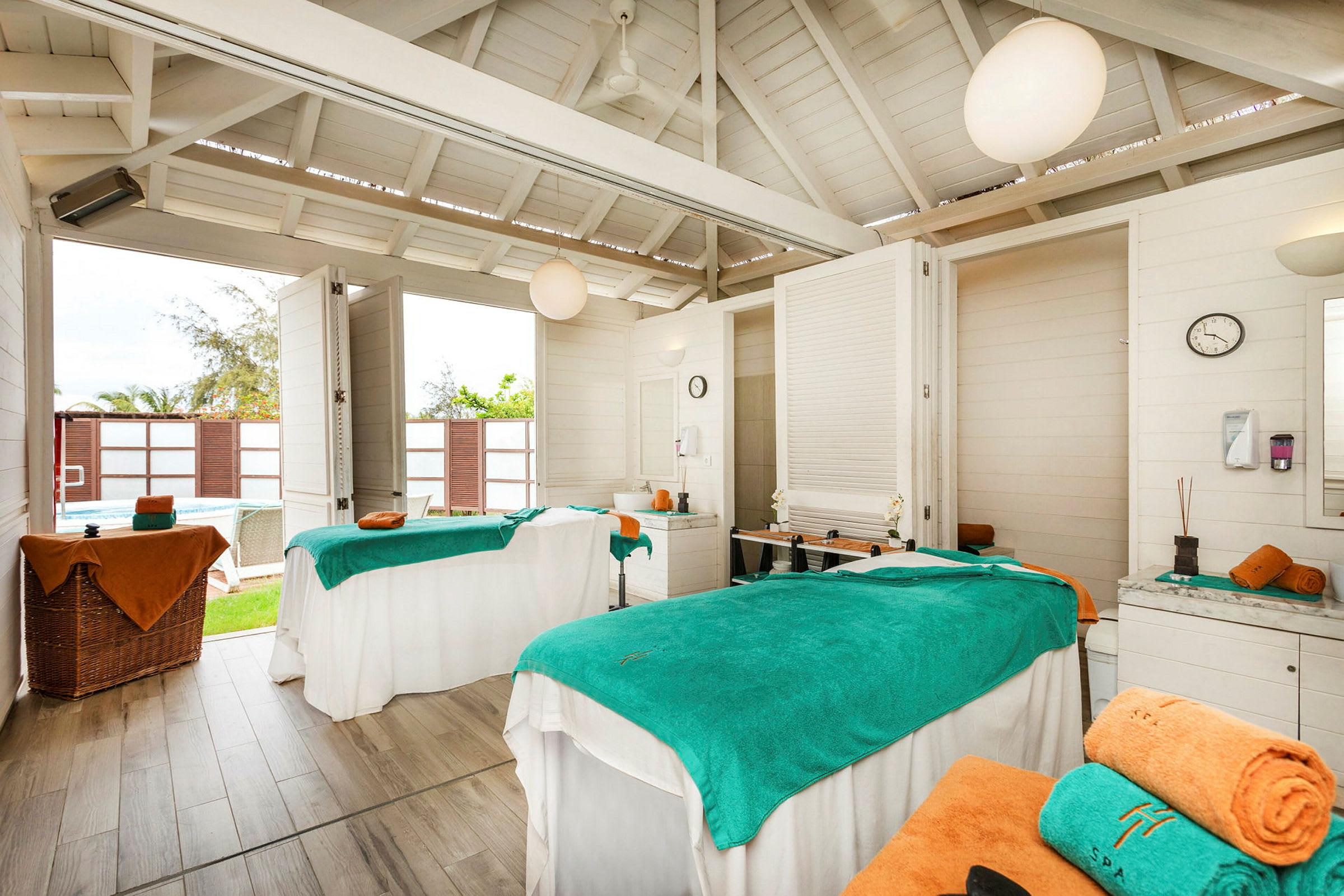 Ett spa-rum med två massagebänkar täckta med gröna och orange handdukar. (AI-genererad text)