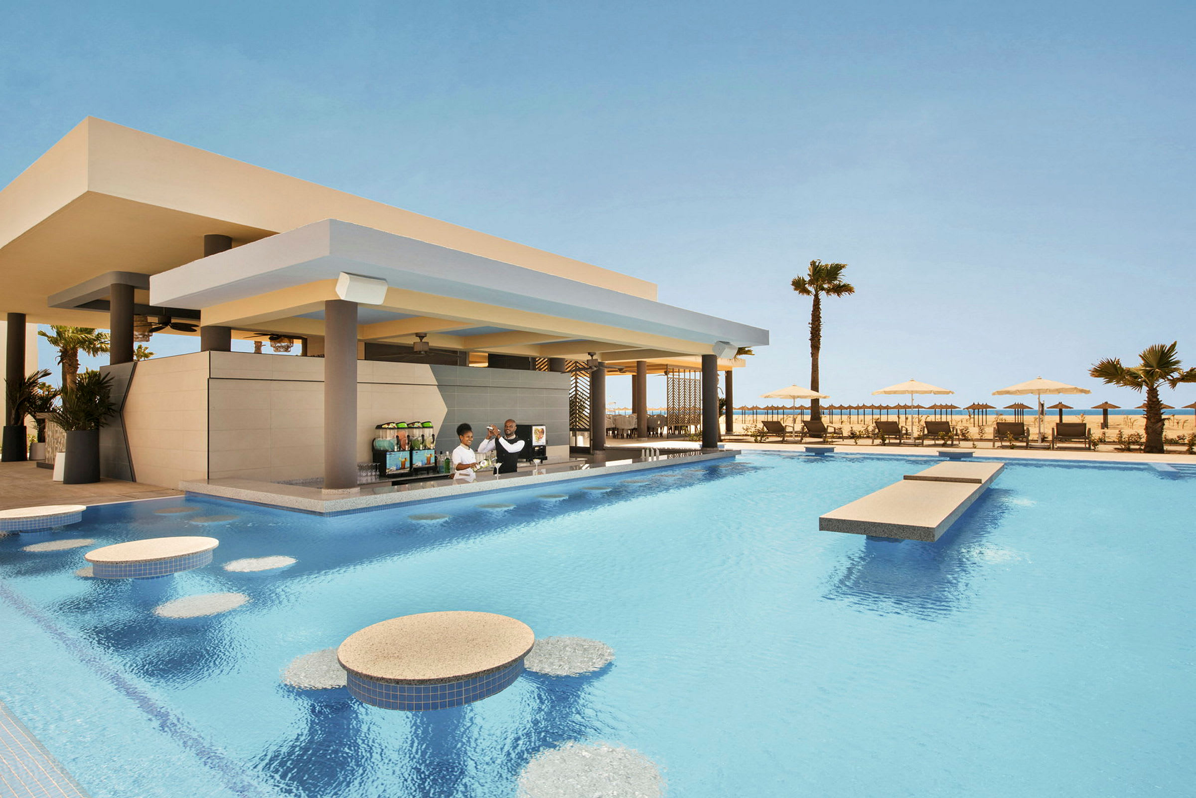En pool med en poolbar under tak, solstolar och parasoller i bakgrunden. (AI-genererad text)