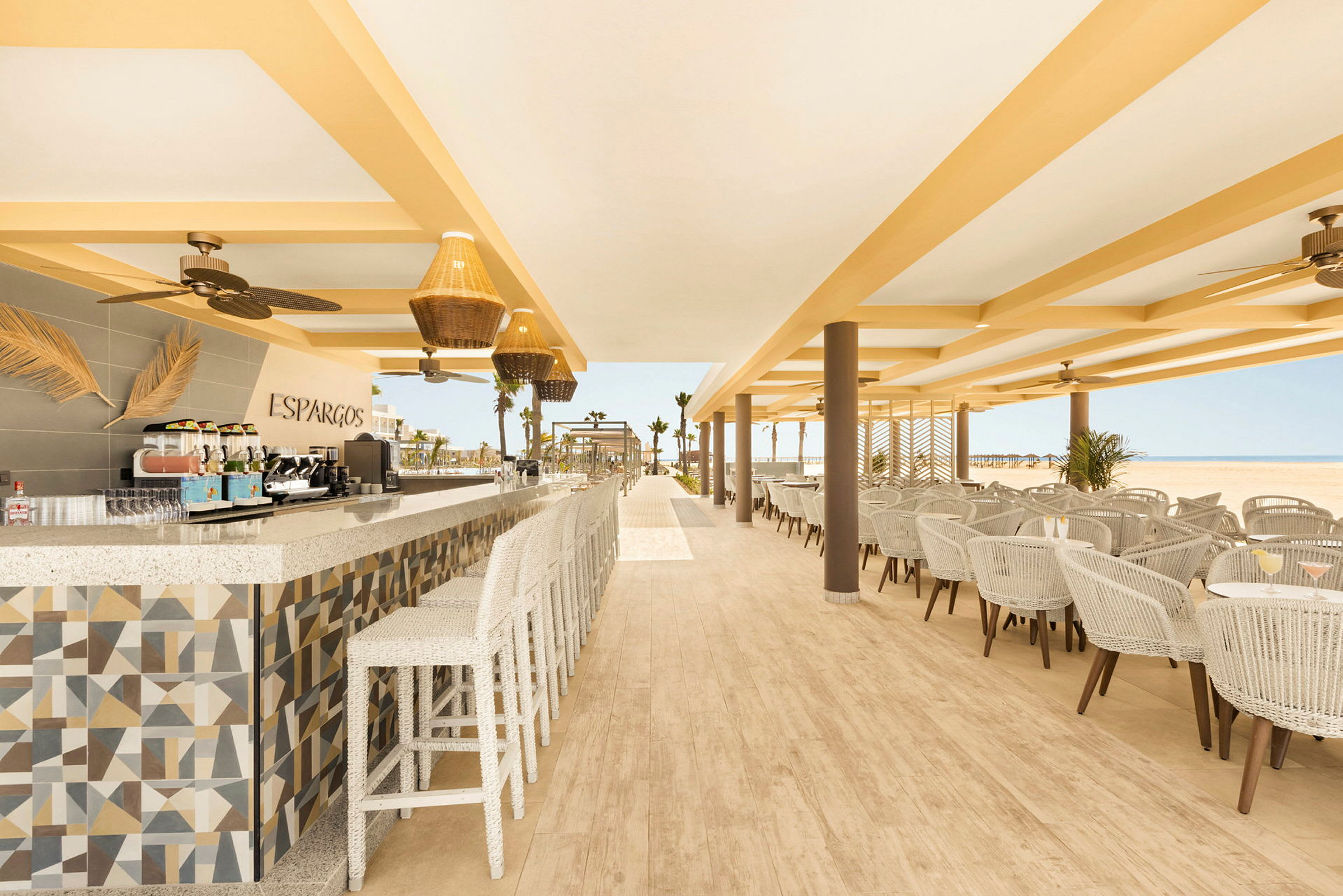 En öppen och ljus restaurang med sittplatser, tak, fläktar och ett välorganiserat matlagningsområde. (AI-genererad text)