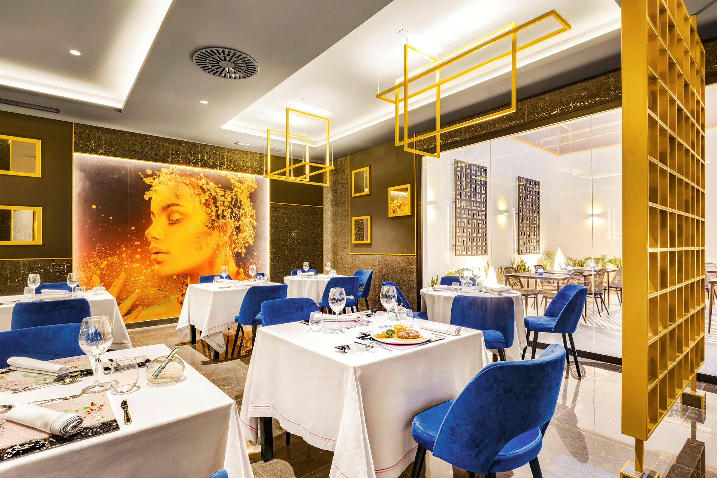 En elegant restaurang med blå stolar, vita dukar och modern inredning. (AI-genererad text)