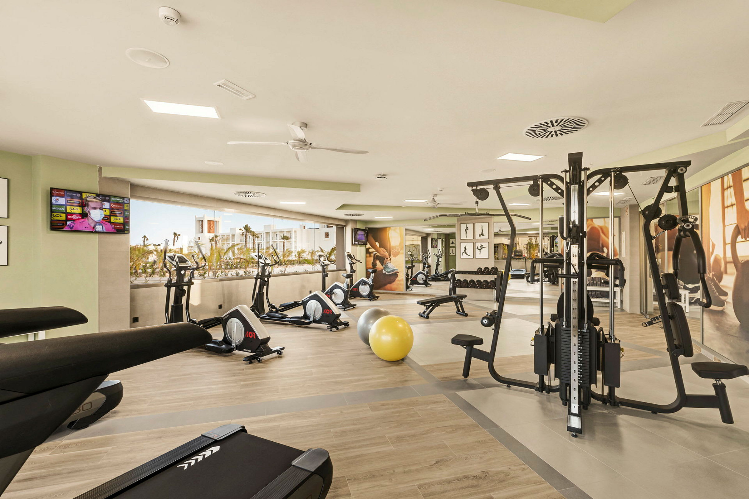 Ett ljust och modernt gym med träningsmaskiner, viktbank och träningsbollar. (AI-genererad text)