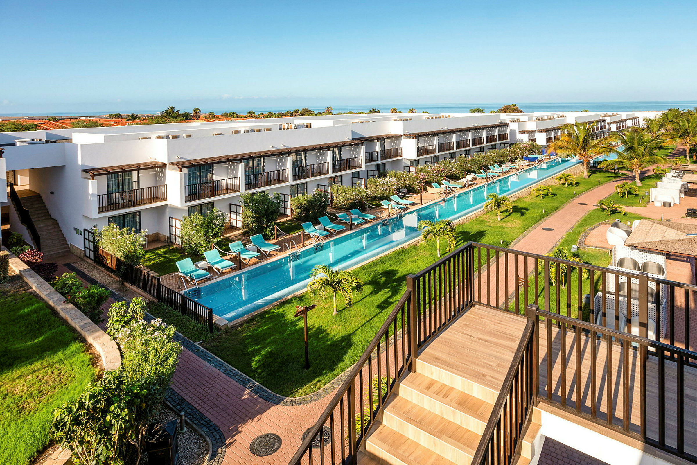 En översikt av en resort med byggnader, en lång pool och grönskande omgivningar. (AI-genererad text)