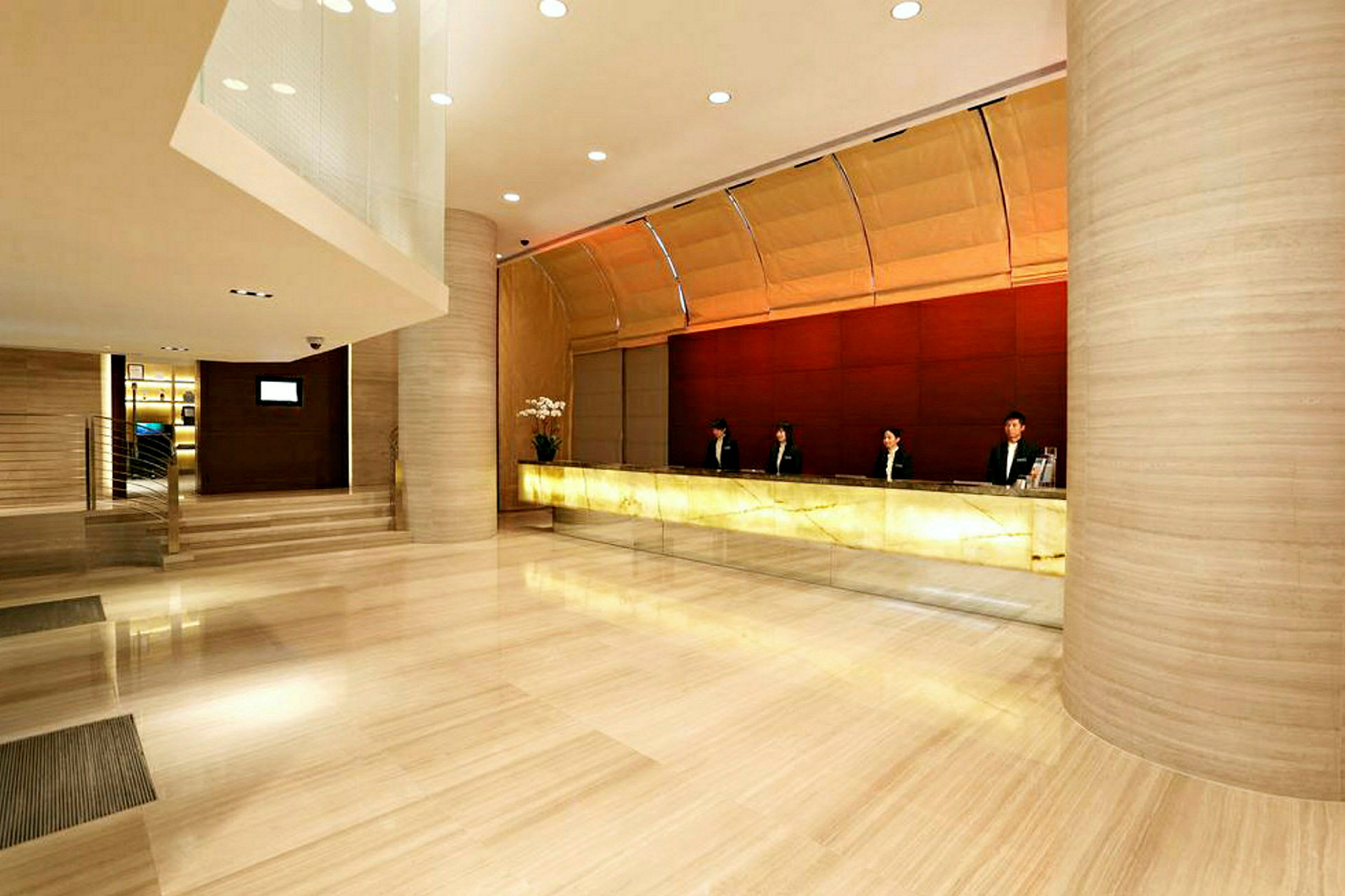 Bild av en hotellreception med en lång receptionsdisk och personal i uniform. Golvet är av polerad sten. (AI-genererad text)