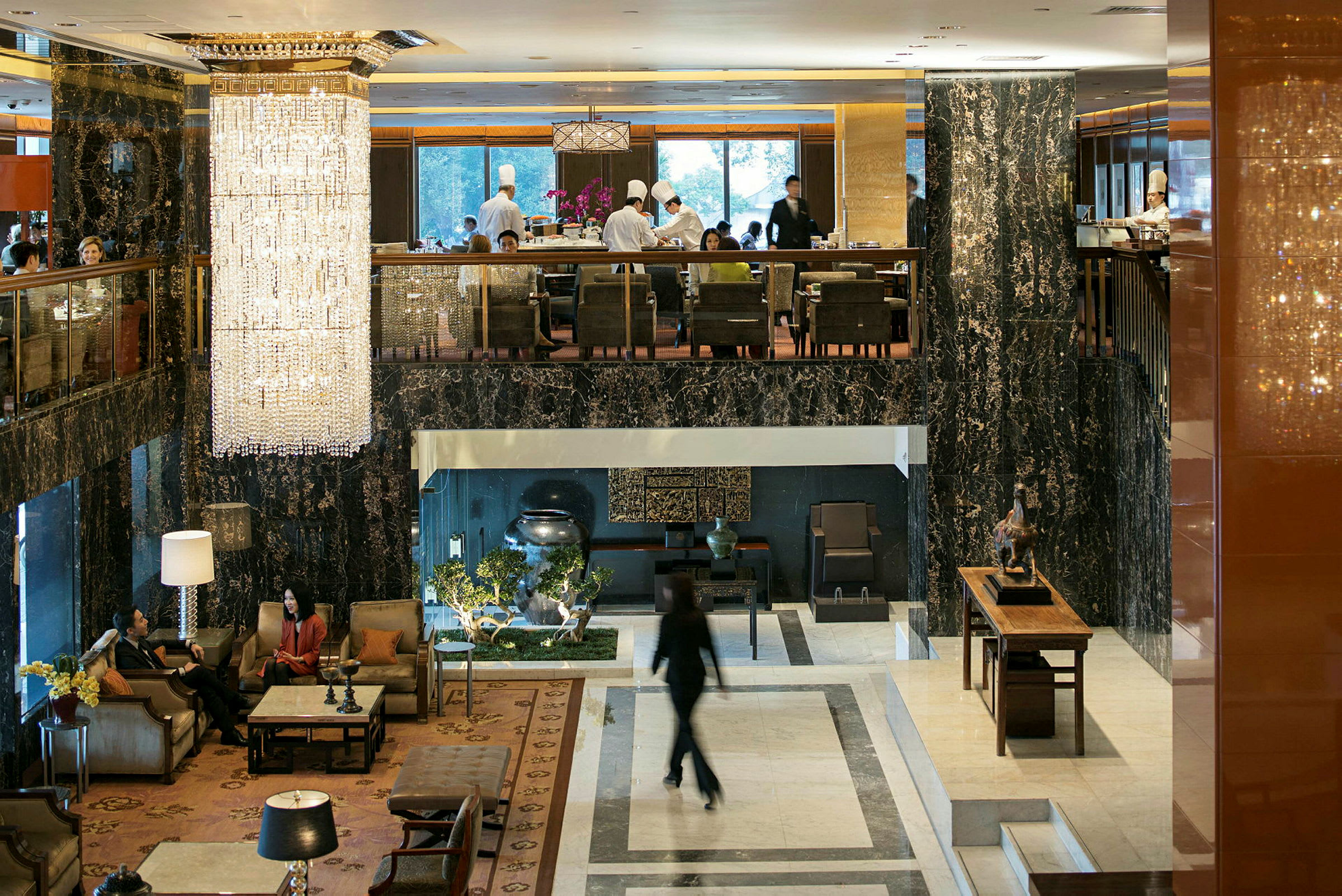 Hotellobby med eleganta möbler, stora fönster och en stor kristallkrona som hänger från taket. (AI-genererad text)