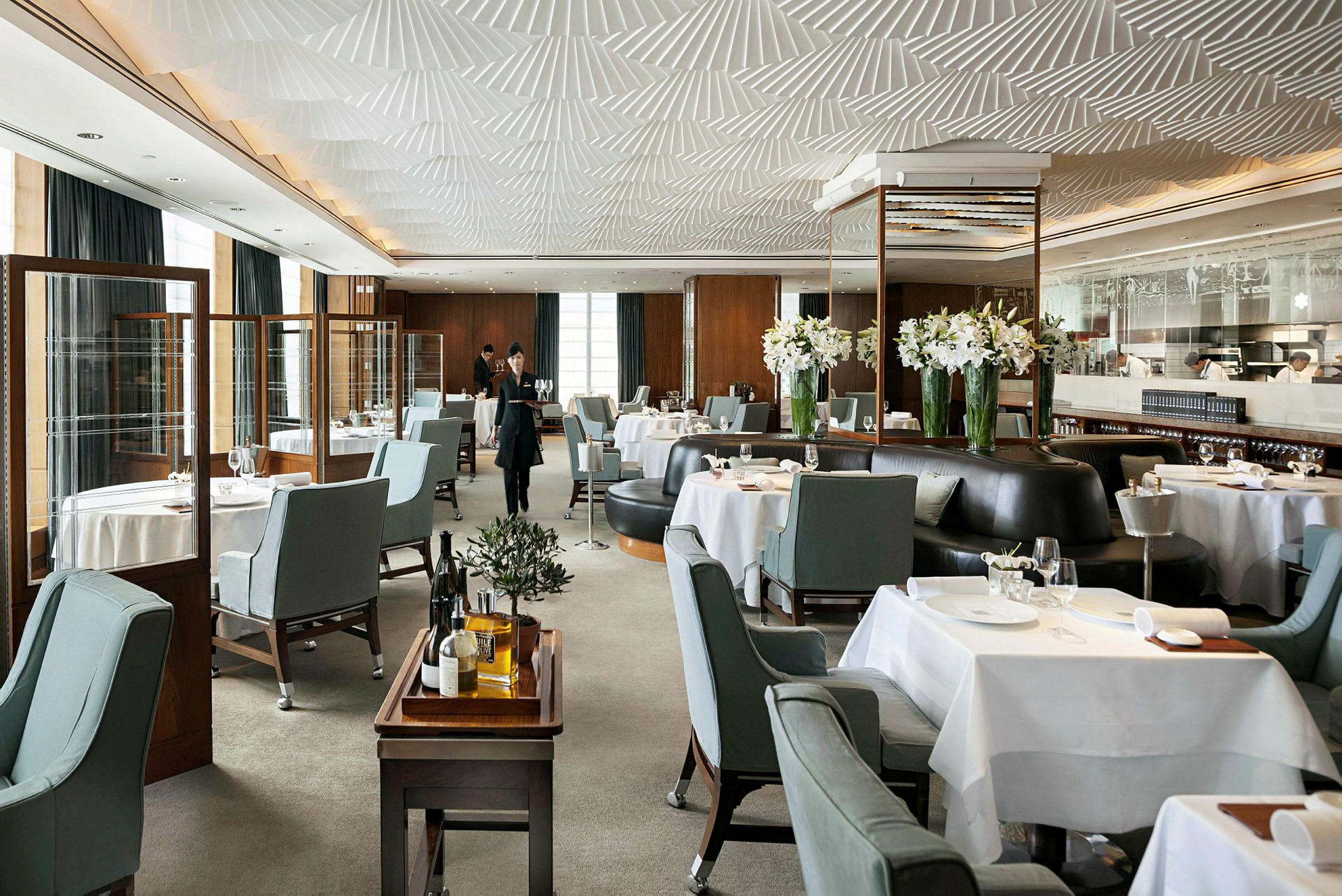 Det är en elegant restaurang med uppdukade bord, blågrå stolar och dekorationer med vita blommor. (AI-genererad text)