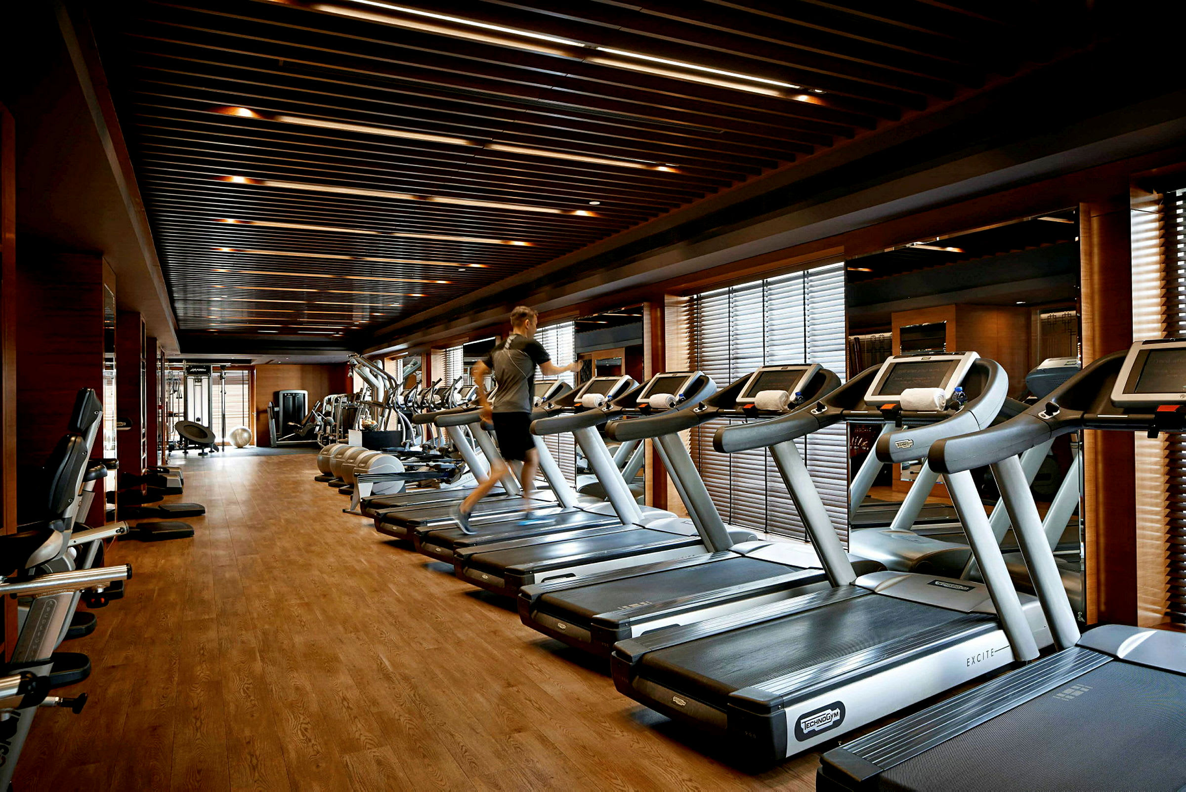 En gymmiljö med löpband, träningsmaskiner och en person som tränar. (AI-genererad text)