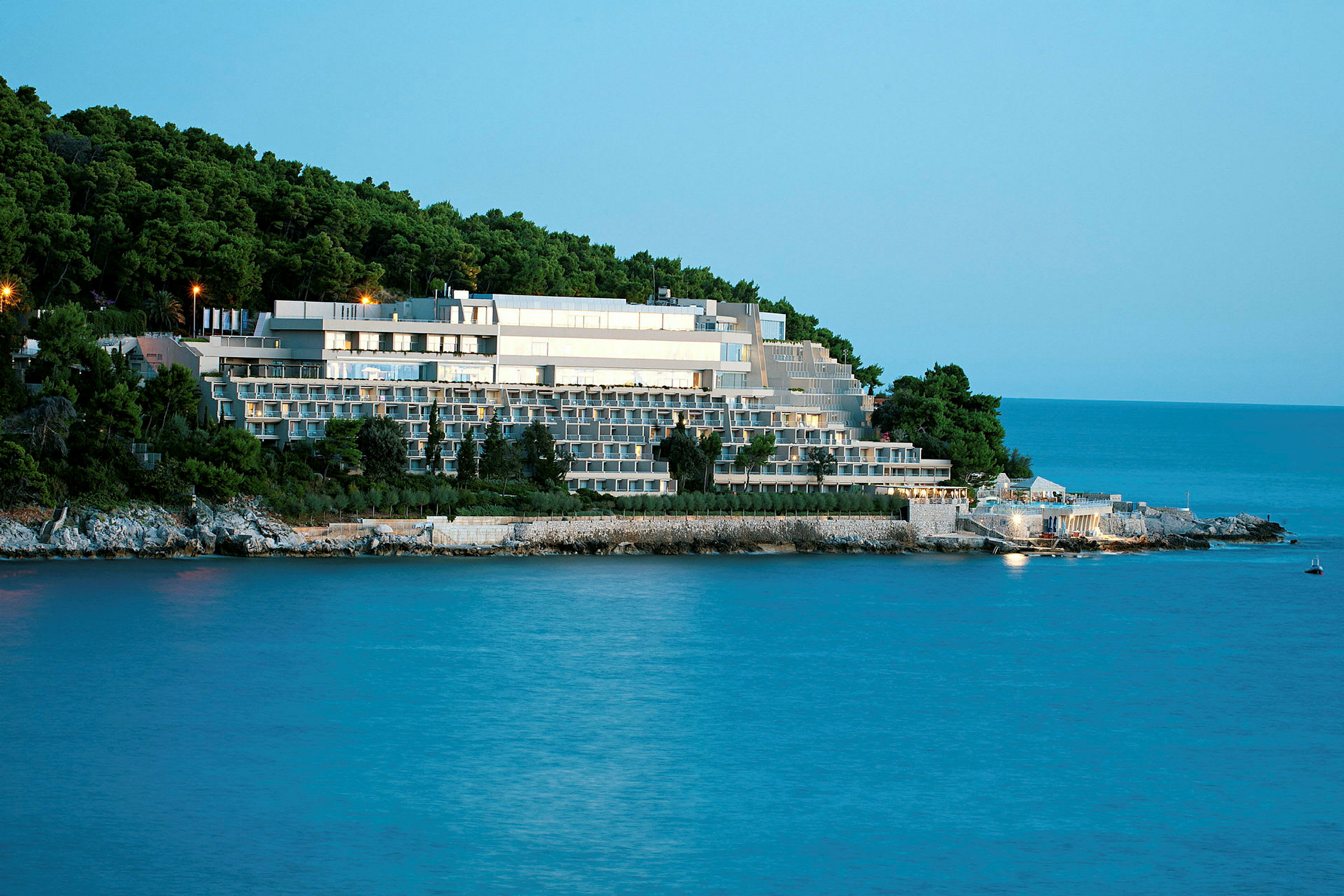 Ett större hotellkomplex beläget vid havet, omringat av grönskande skog. (AI-genererad text)