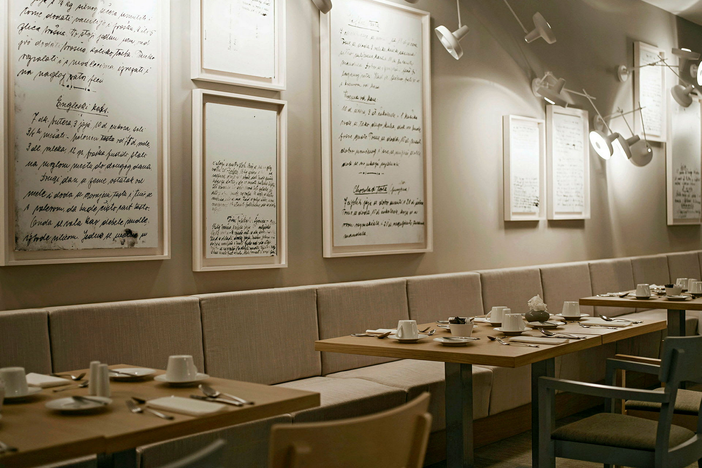 En elegant restaurang med bord klädda för middag och dekorerade med minimalistiska tavlor på väggen. (AI-genererad text)
