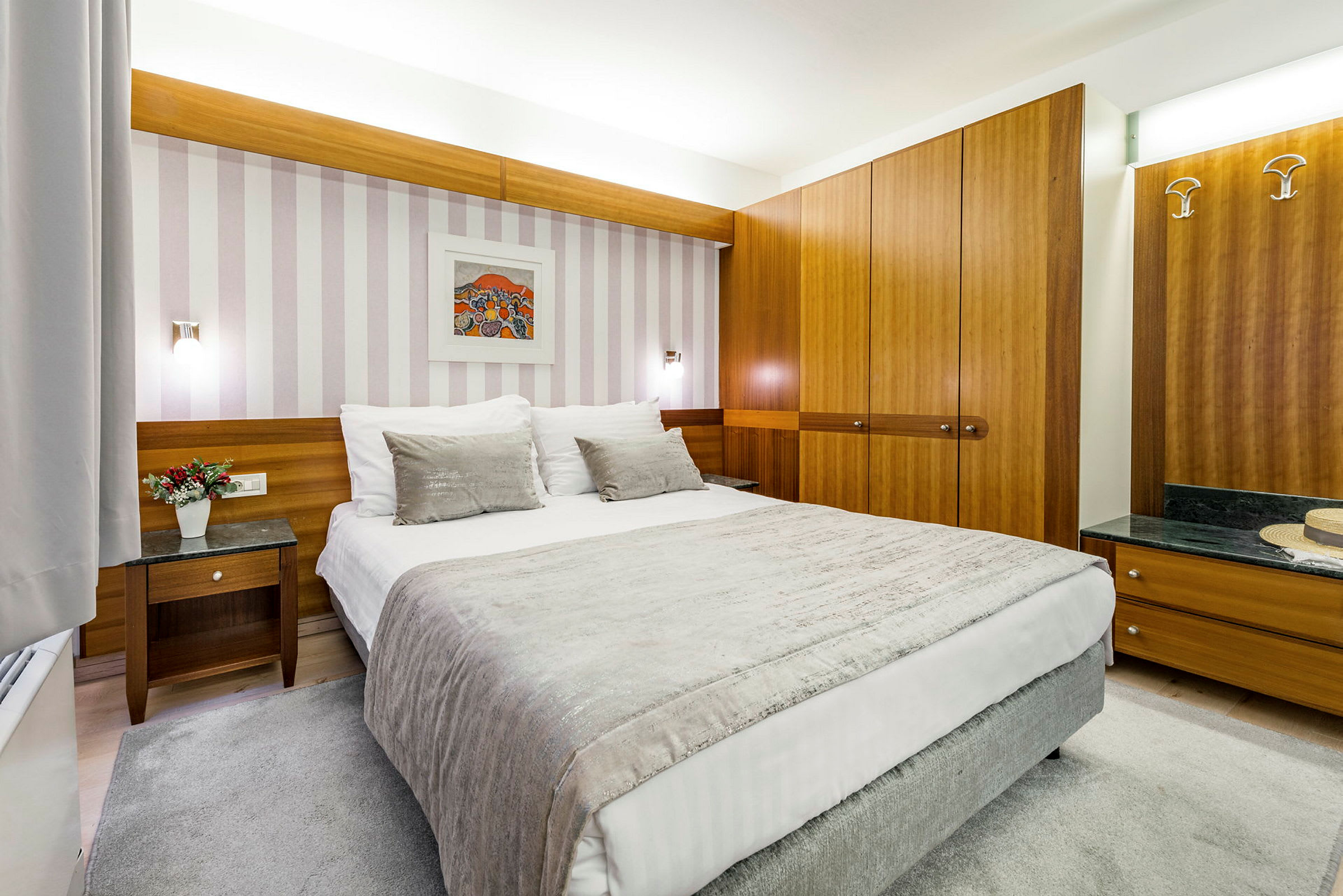 Ett hotellrum med en bäddad säng, träinredning och väggkonst. (AI-genererad text)