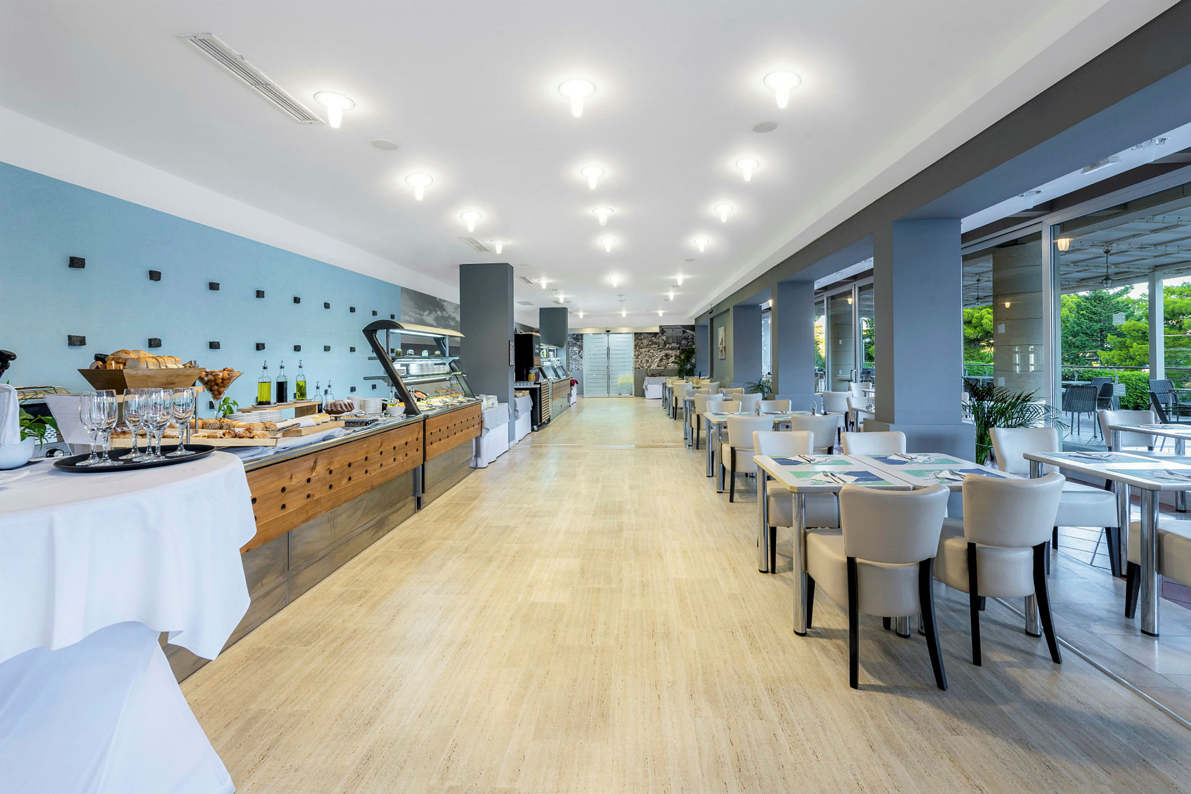 En ljus och modern restaurang med uppdukad buffé till vänster och sittplatser till höger. (AI-genererad text)