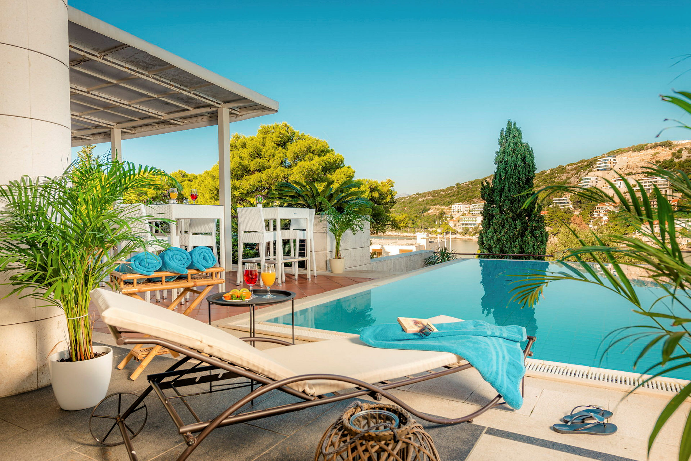 En solstol och bord vid en pool med utsikt över en grönskande bakgrund. (AI-genererad text)