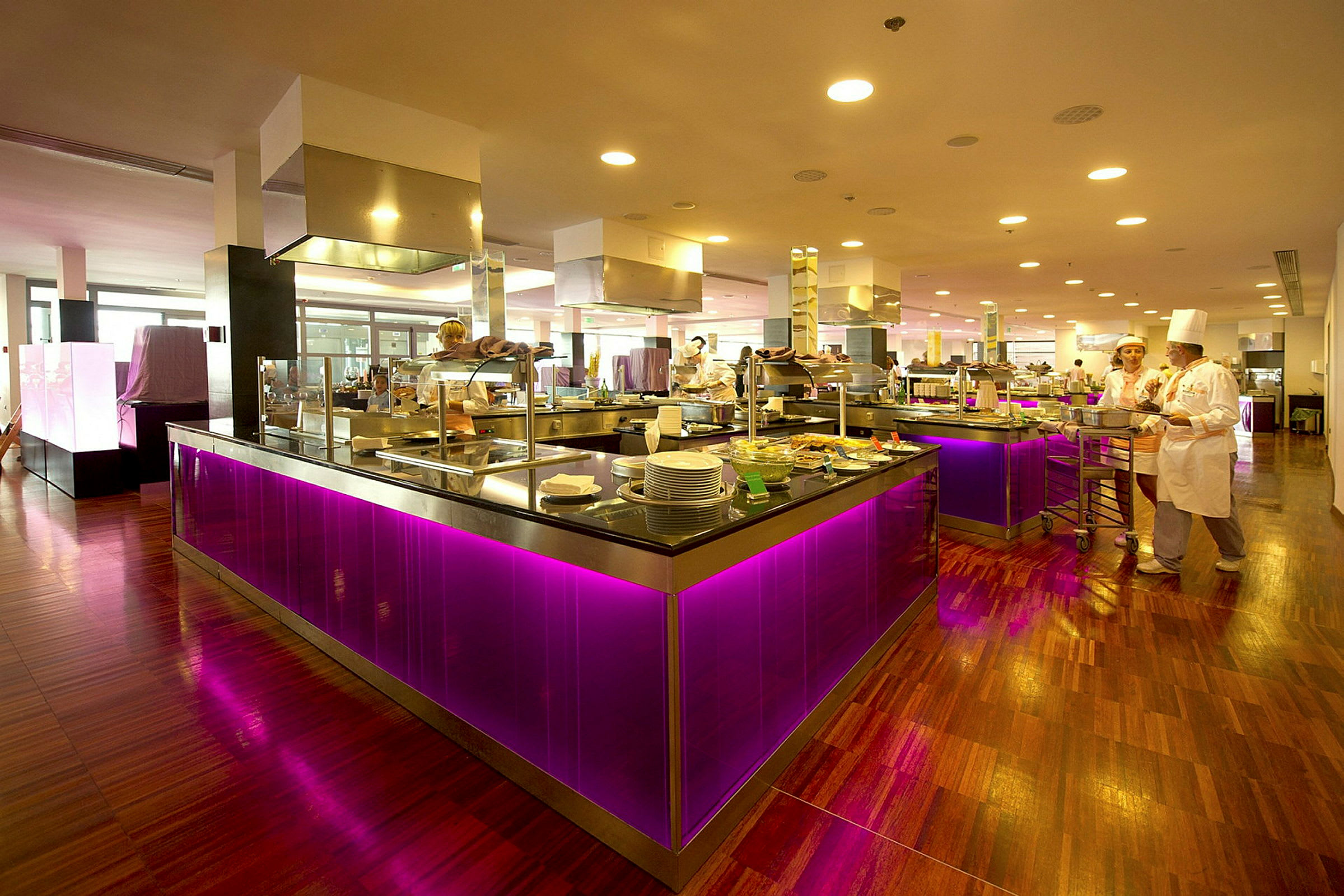 Bild av en restaurang eller bufféområde med moderna och färgglada inredningsdetaljer, inklusive lysande lila belysning under diskarna. (AI-genererad text)