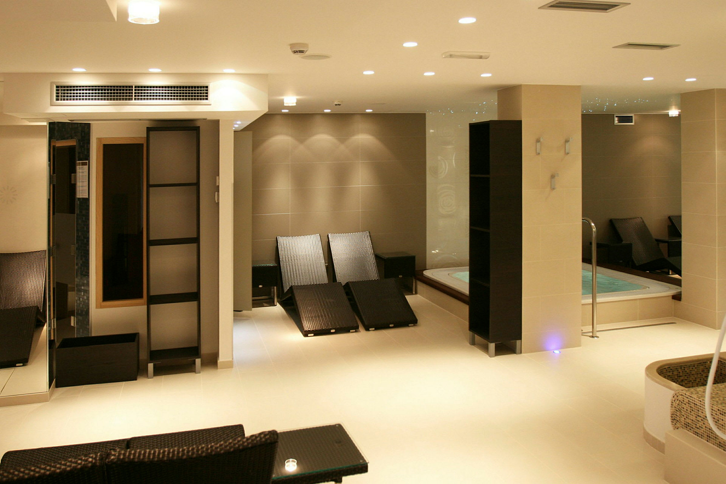 Ett modernt spa med jacuzzi, solstolar och stilren inredning. (AI-genererad text)