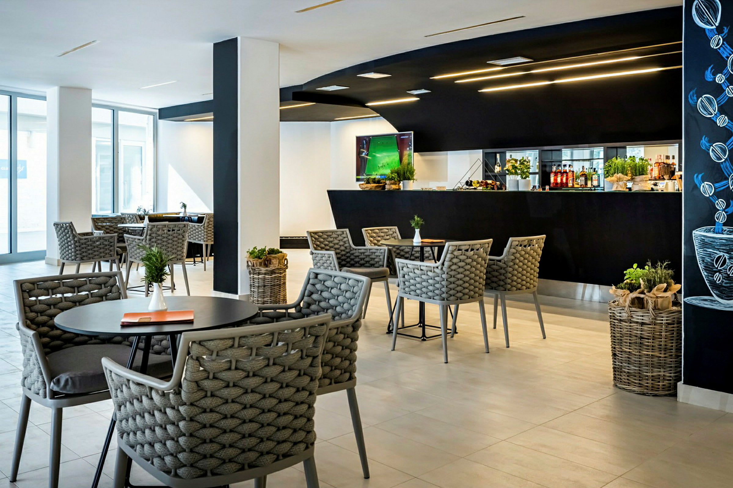 Ett modernt kafé med bord och stolar samt en svart bardisk i bakgrunden. (AI-genererad text)