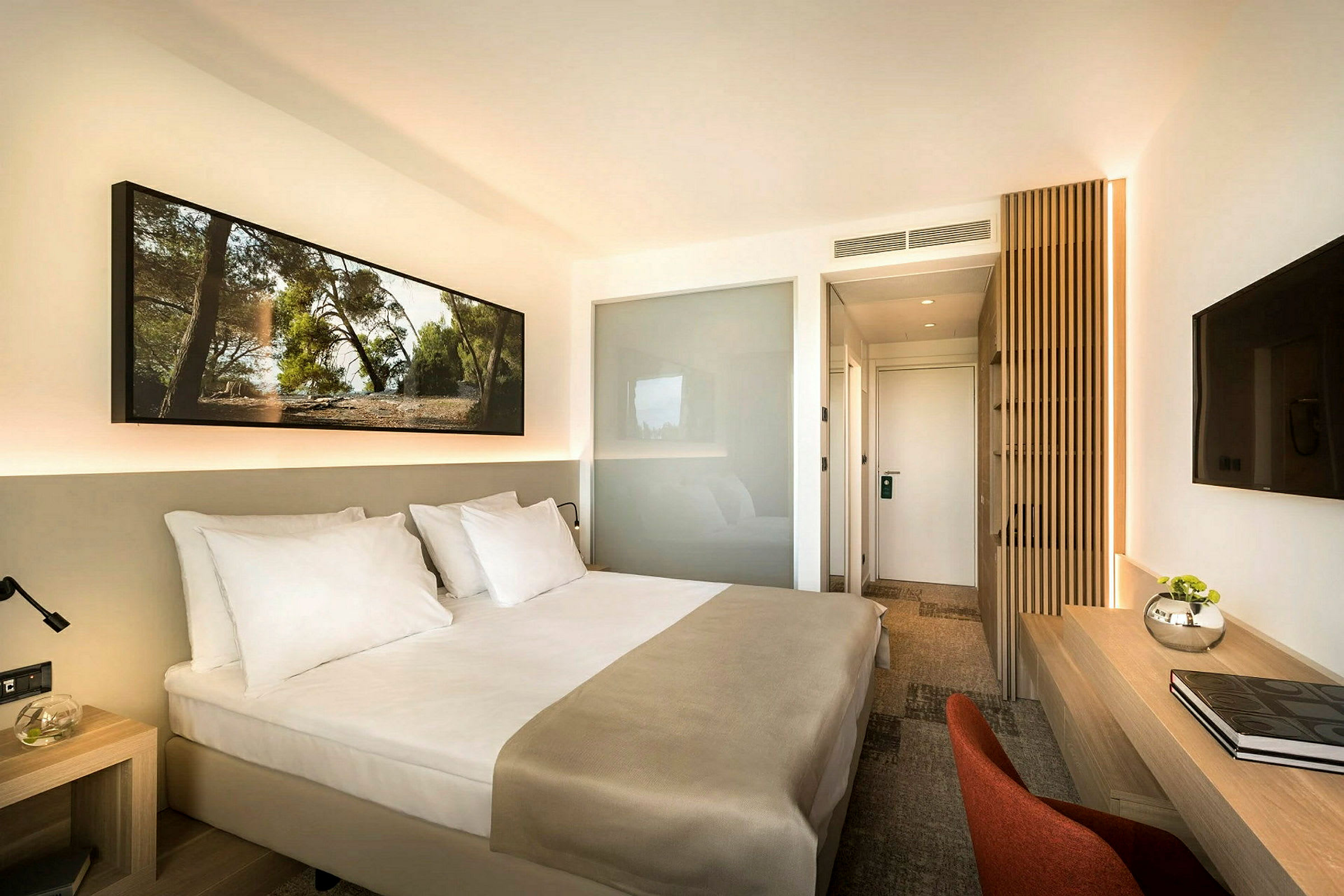 Hotellrum med en dubbelsäng, ett skrivbord och en TV på väggen. (AI-genererad text)