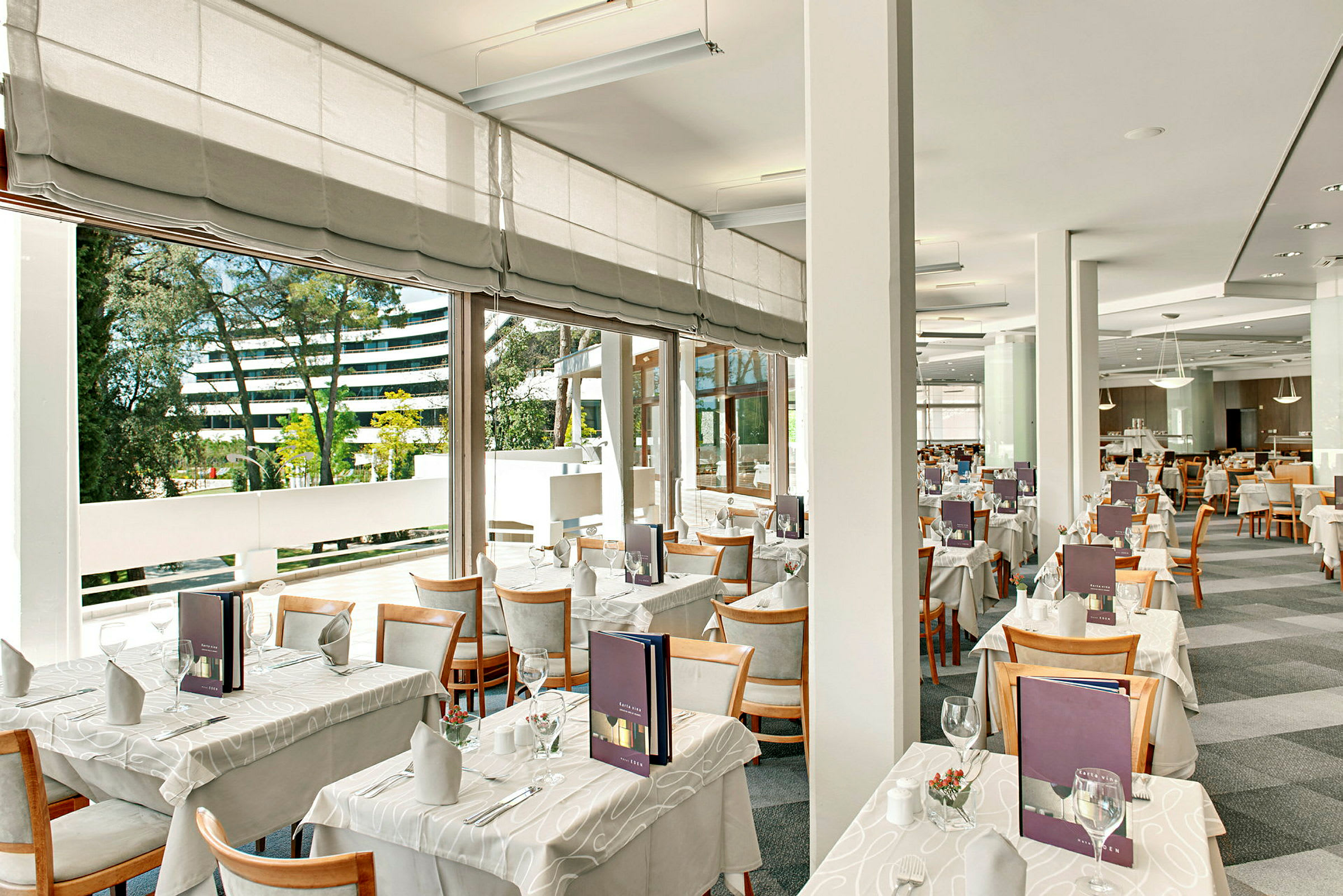 Modernt och ljust restaurangområde med dukade bord och stora fönster. (AI-genererad text)