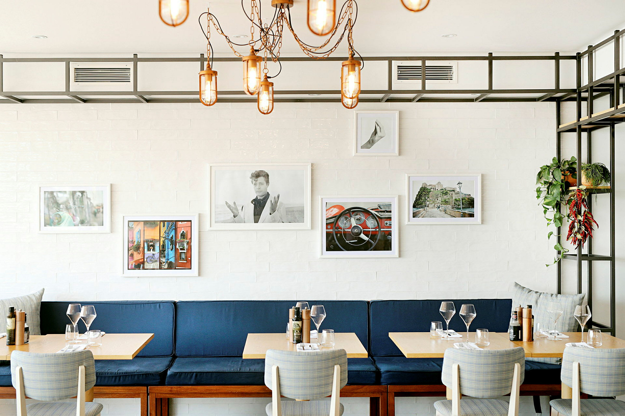 En restaurang med blå bänk, träbord och dekorativa bilder på väggarna. (AI-genererad text)