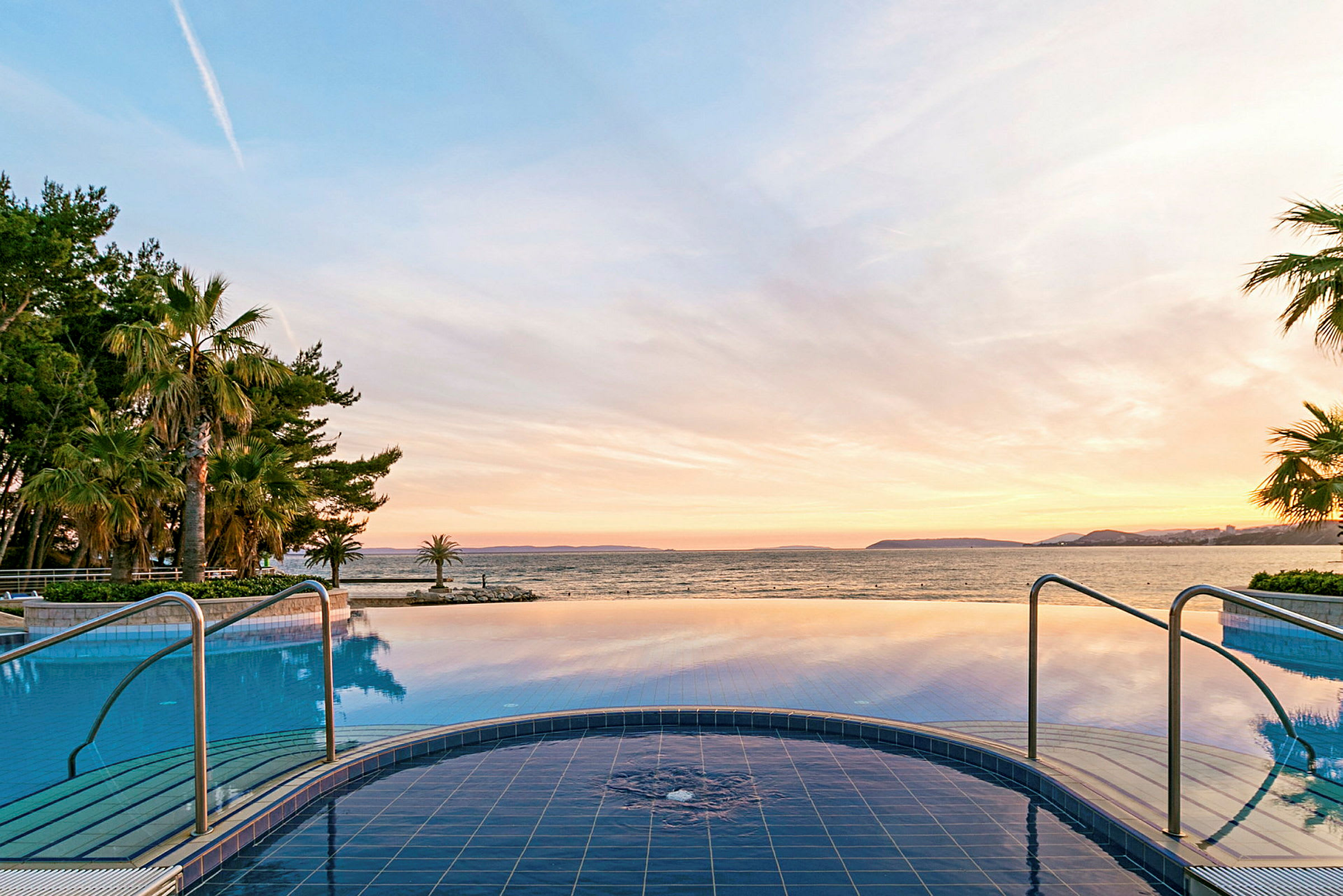 En pool med utsikt över havet och solnedgången. (AI-genererad text)