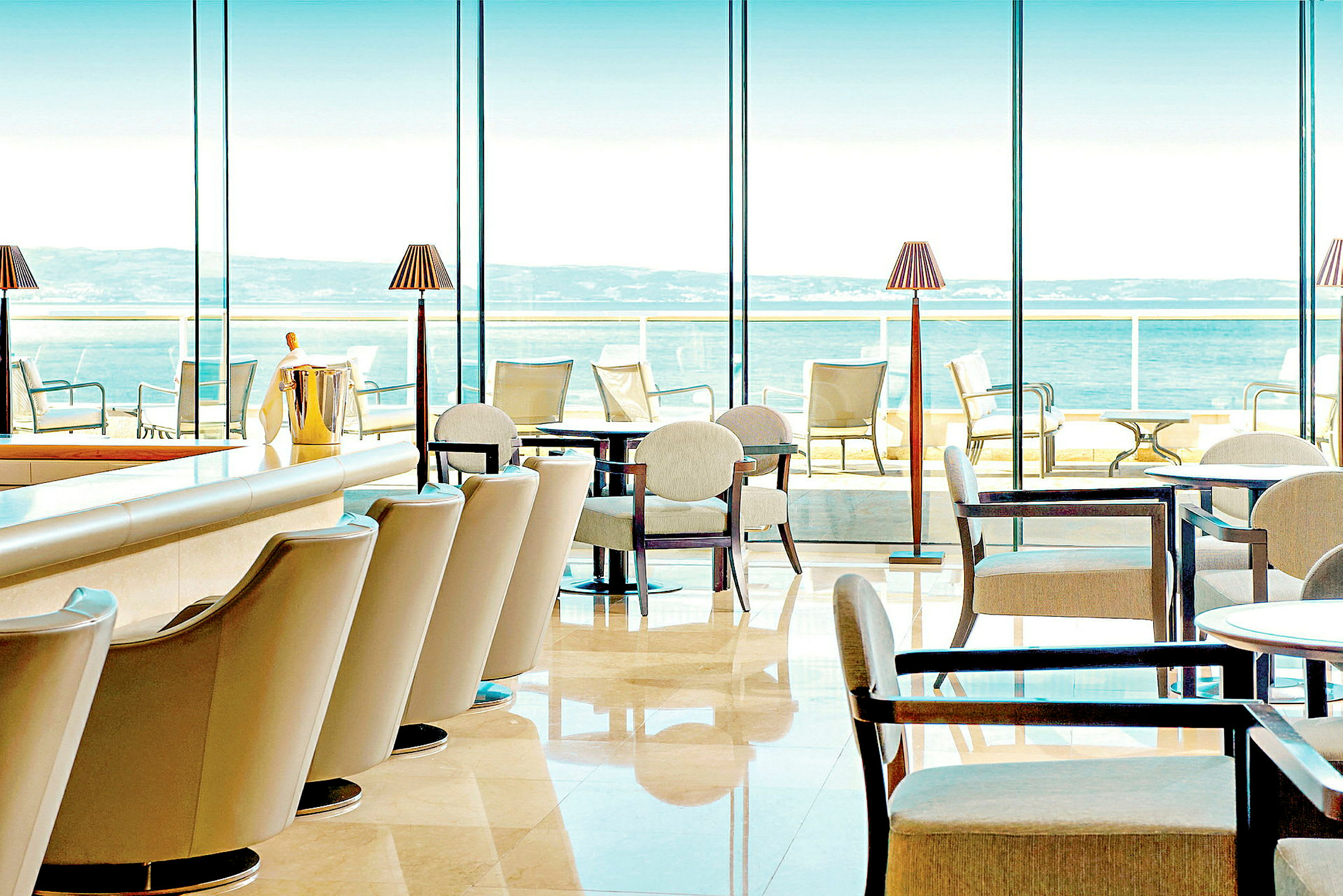 Restaurang med moderna möbler och stora fönster med utsikt över havet. (AI-genererad text)