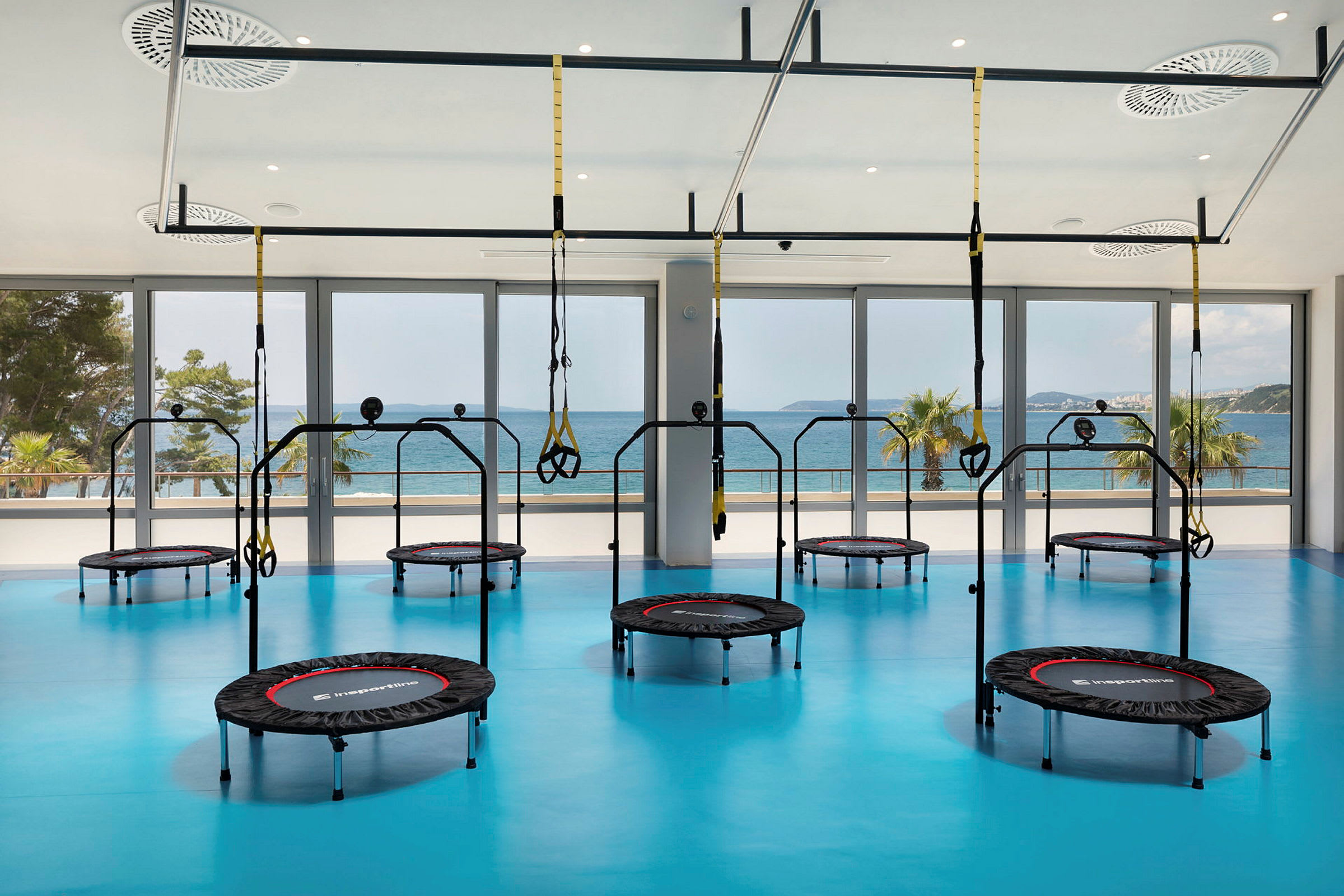 Gym med trampoliner och träningsutrustning, med havsutsikt. (AI-genererad text)