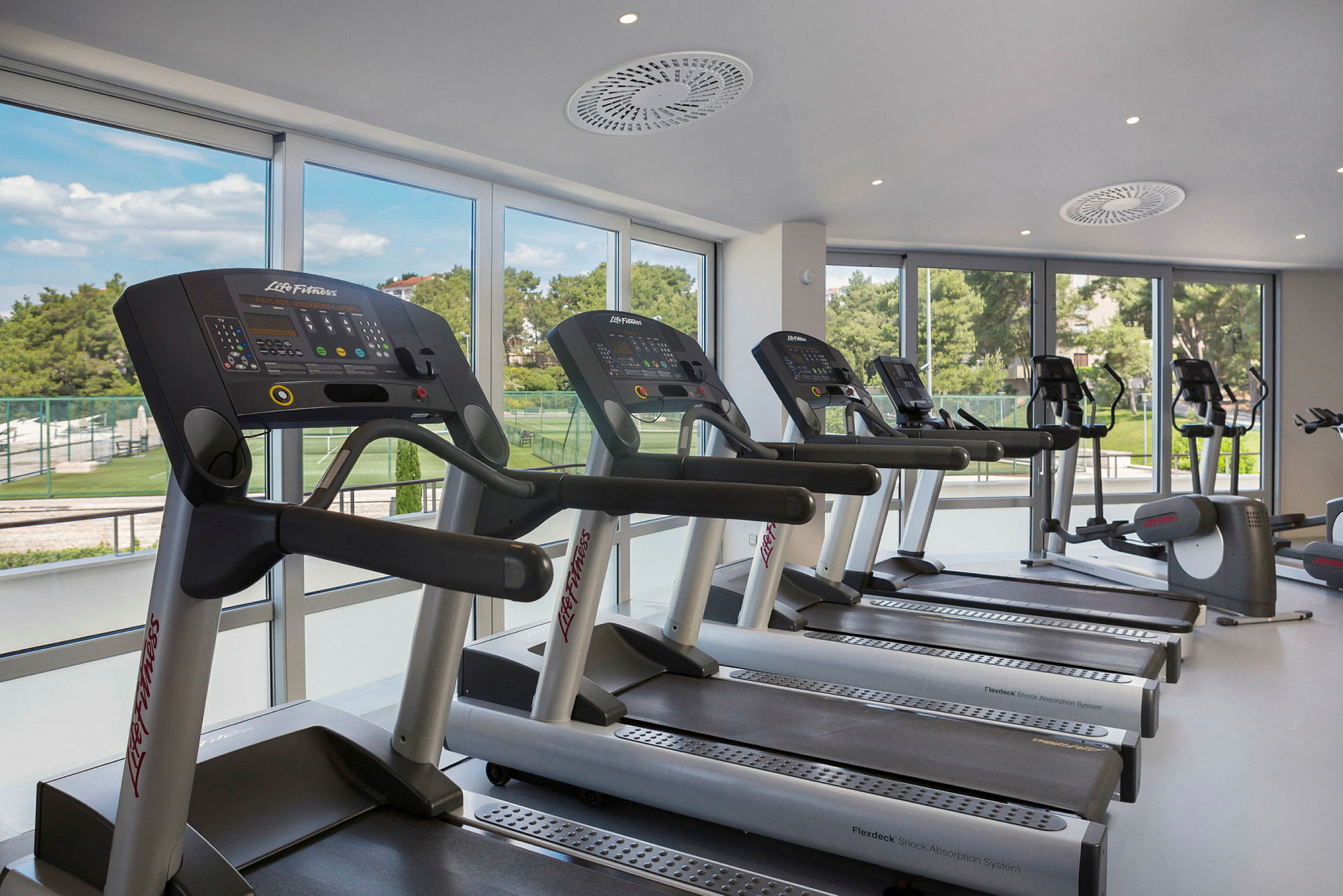 En gym med flera löpband framför fönster. (AI-genererad text)