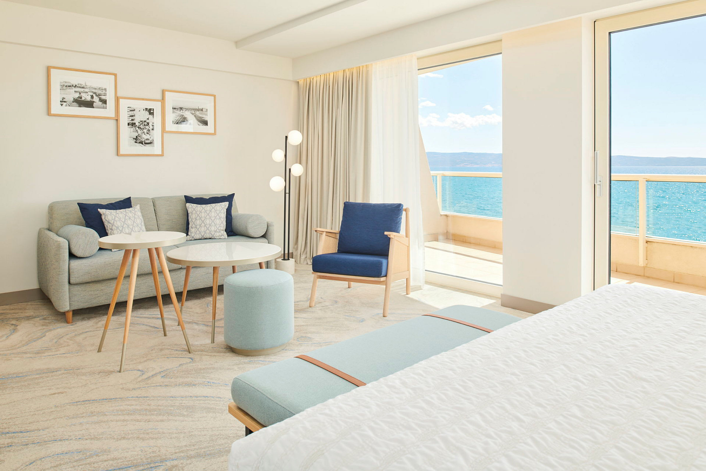 Ljust och modernt hotellrum med sittgrupp och utsikt mot havet. (AI-genererad text)