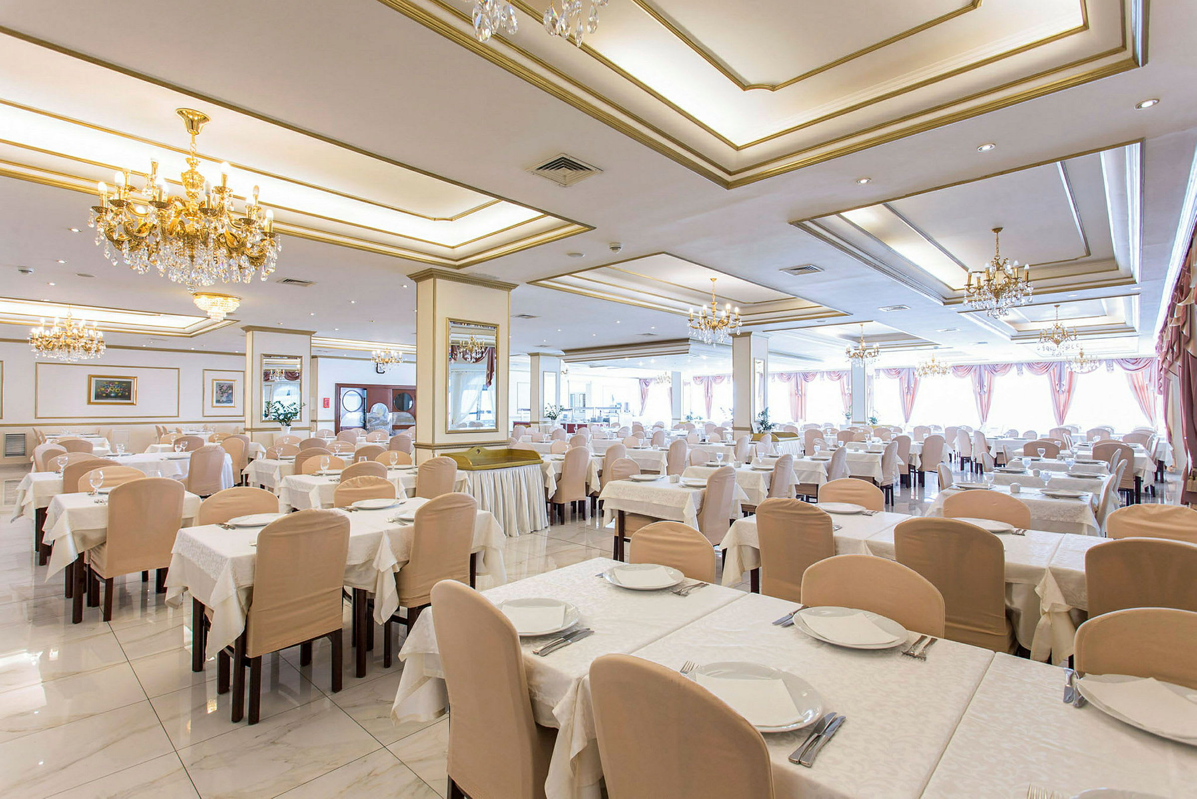 En rymlig restaurang med ljuskronor i taket och dukade bord. (AI-genererad text)