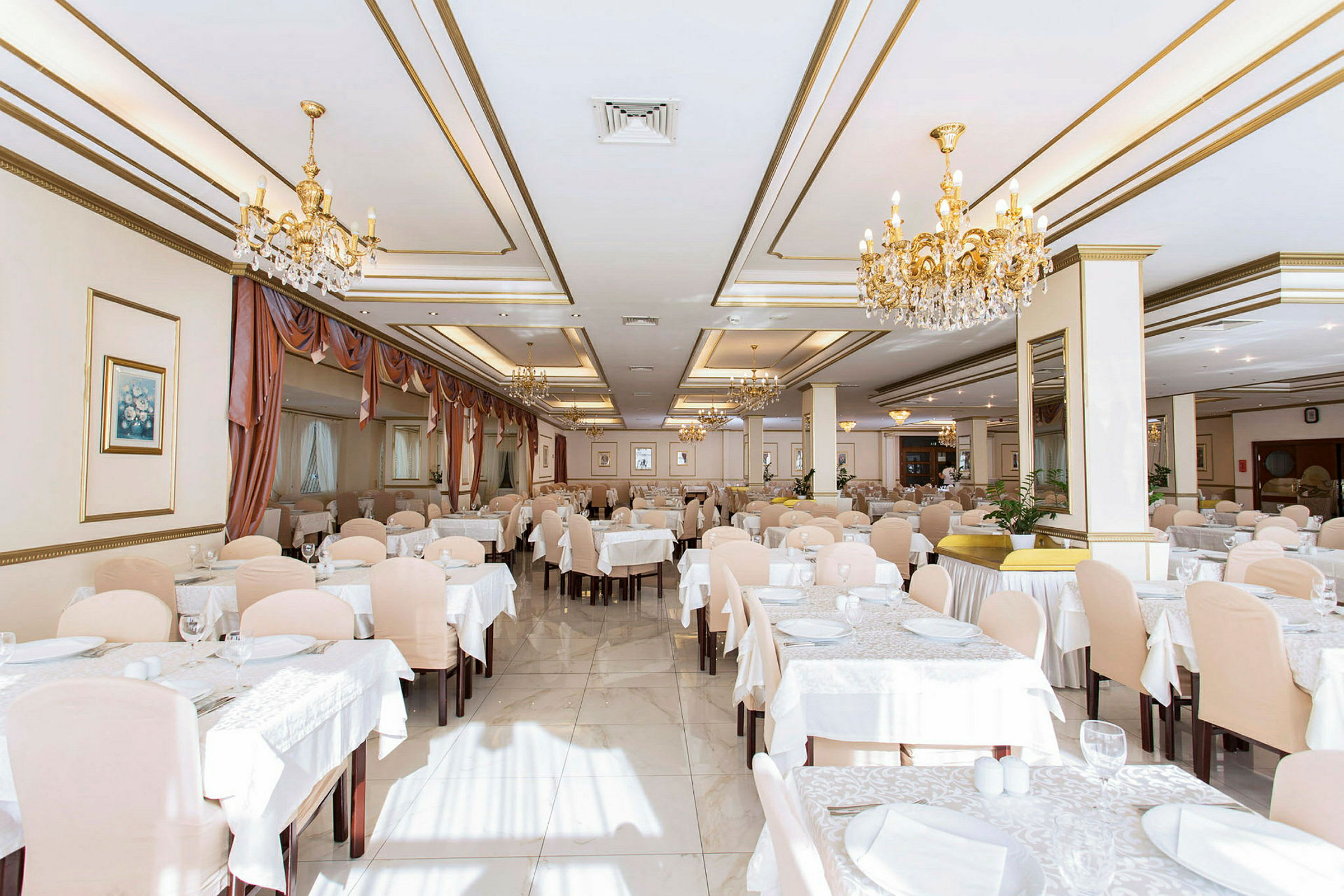 Ett elegant restaurangutrymme med dukade bord och kristallkronor. (AI-genererad text)