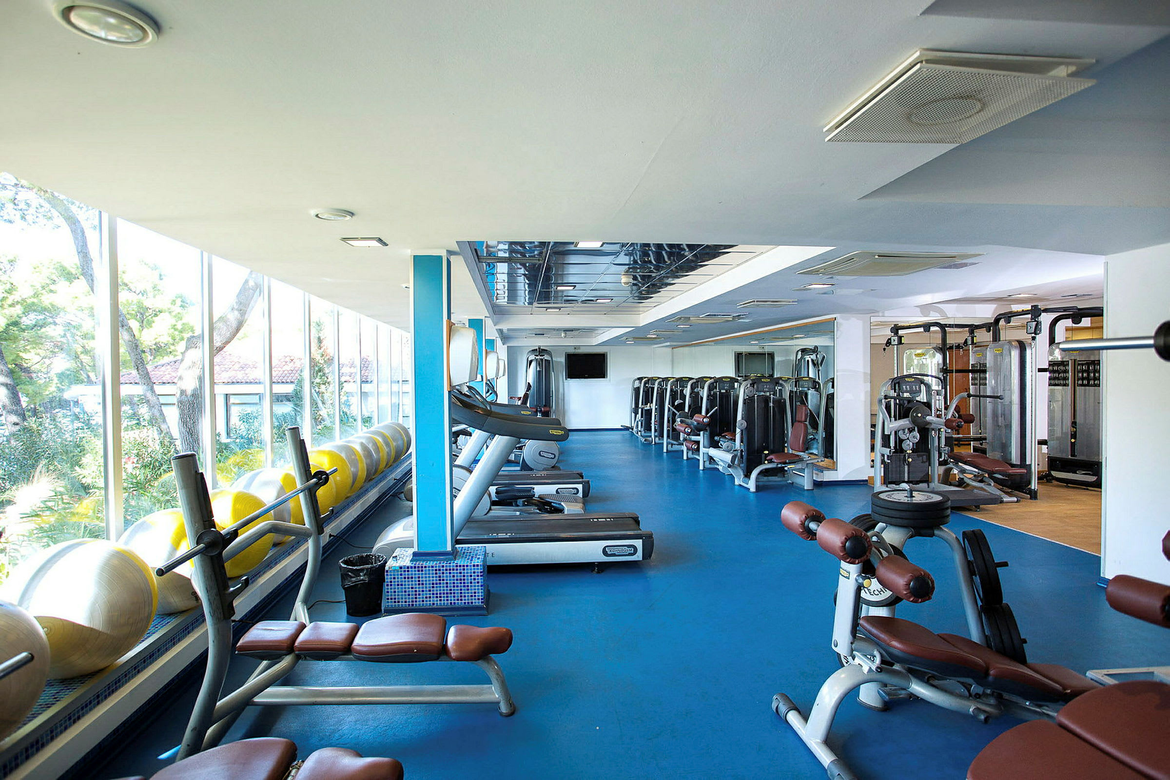 Gym med träningsutrustning och stora fönster. (AI-genererad text)