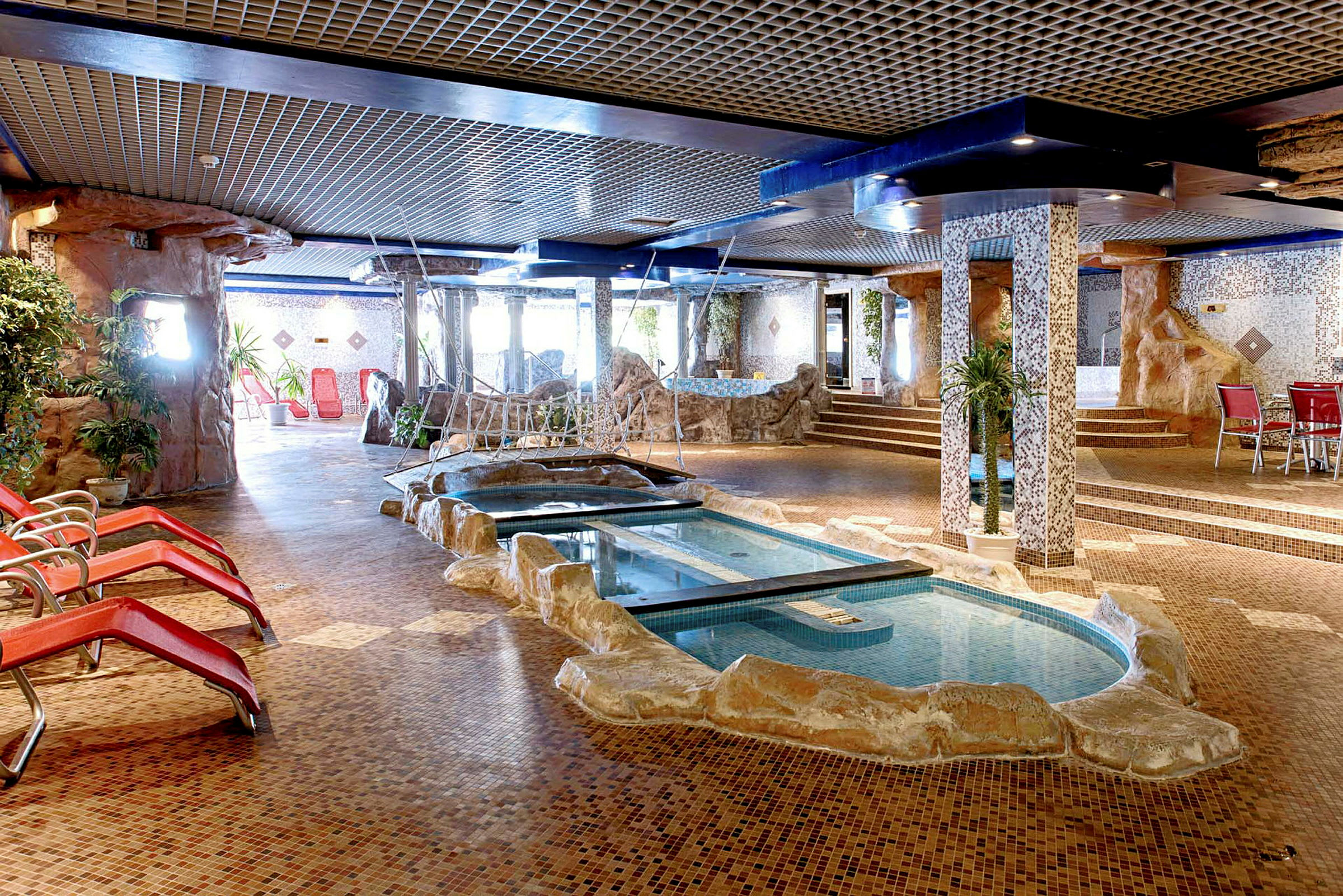 Inomhuspool med omgivande stolar och dekoration. (AI-genererad text)