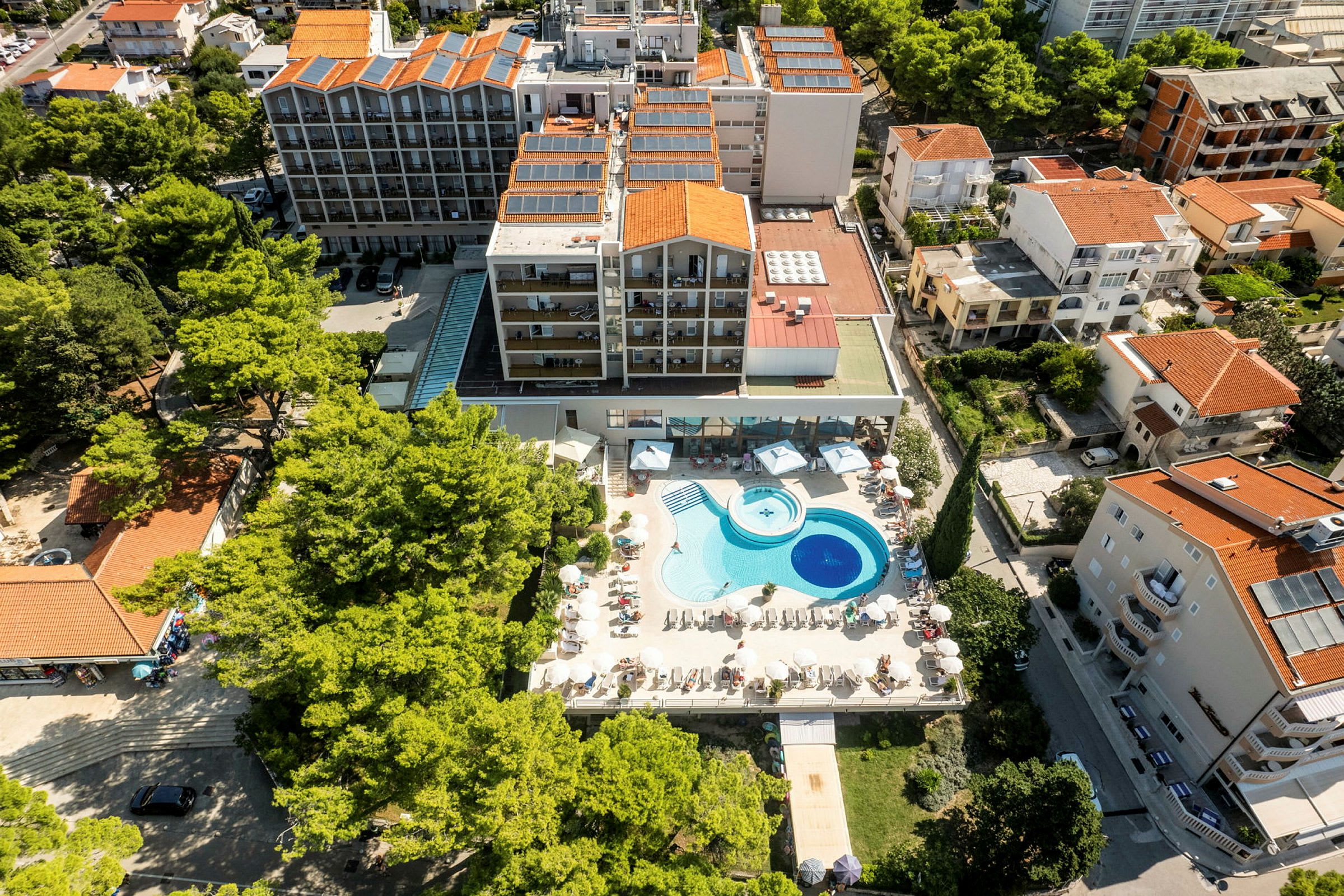 Luftfoto av hotell med poolområde och omgivande byggnader. (AI-genererad text)