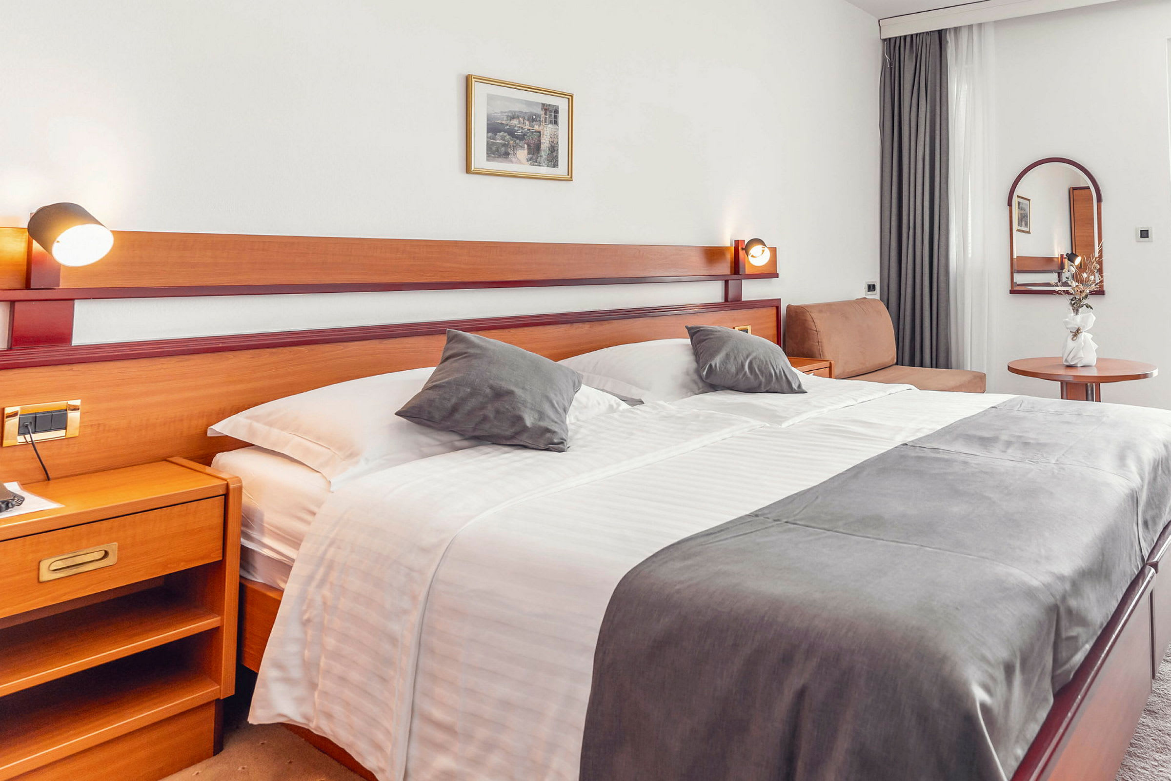 Hotellrum med stor säng, sidobord och dekorationer. (AI-genererad text)