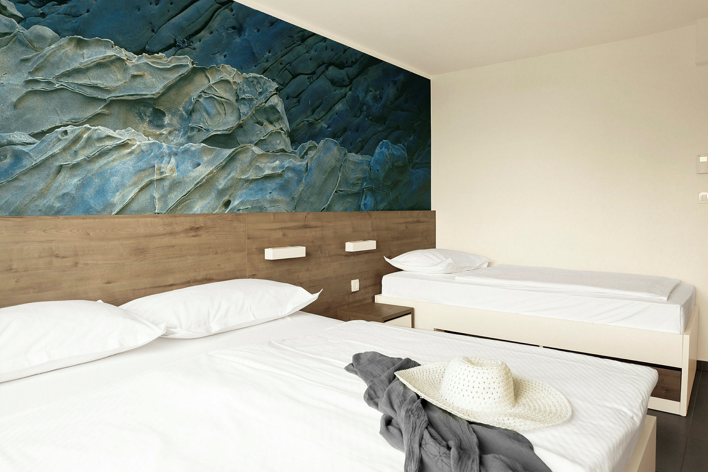 Ett hotellrum med två sängar, vit sängkläder och en dekorativ blå vägg. (AI-genererad text)