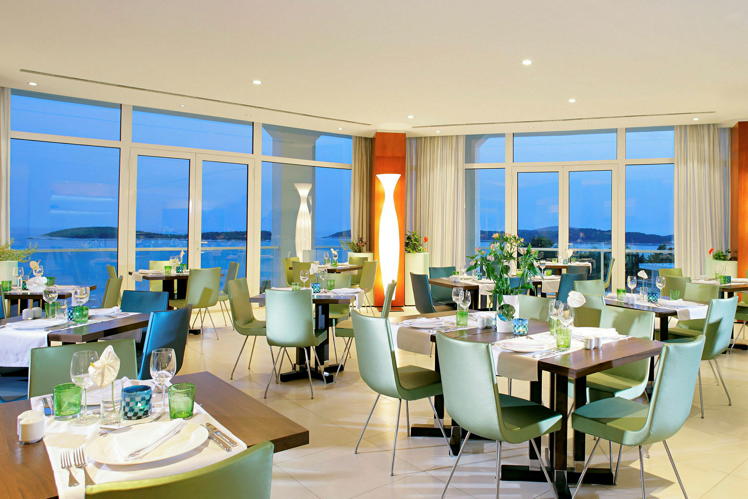 En restaurang med uppdukade bord och stolar, stora fönster med utsikt. (AI-genererad text)