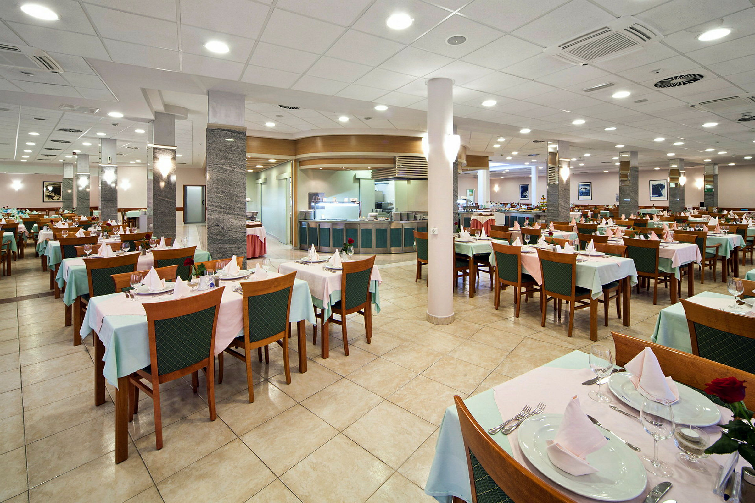 En restaurang med dukade bord och stolar, tom och upplyst. (AI-genererad text)