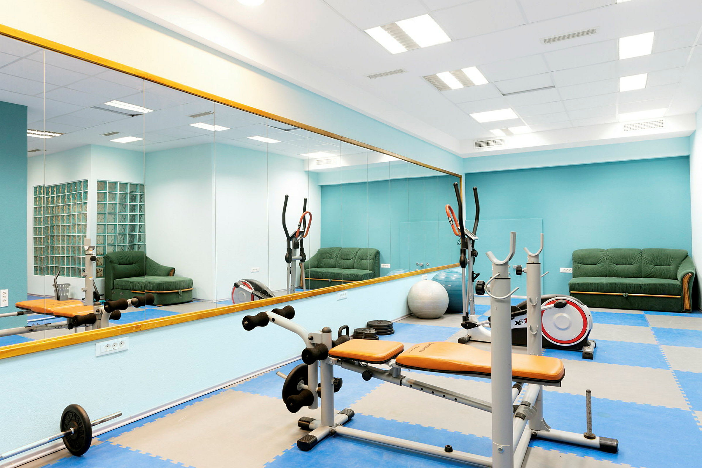 Ett gym med träningsutrustning och spegelvägg. (AI-genererad text)