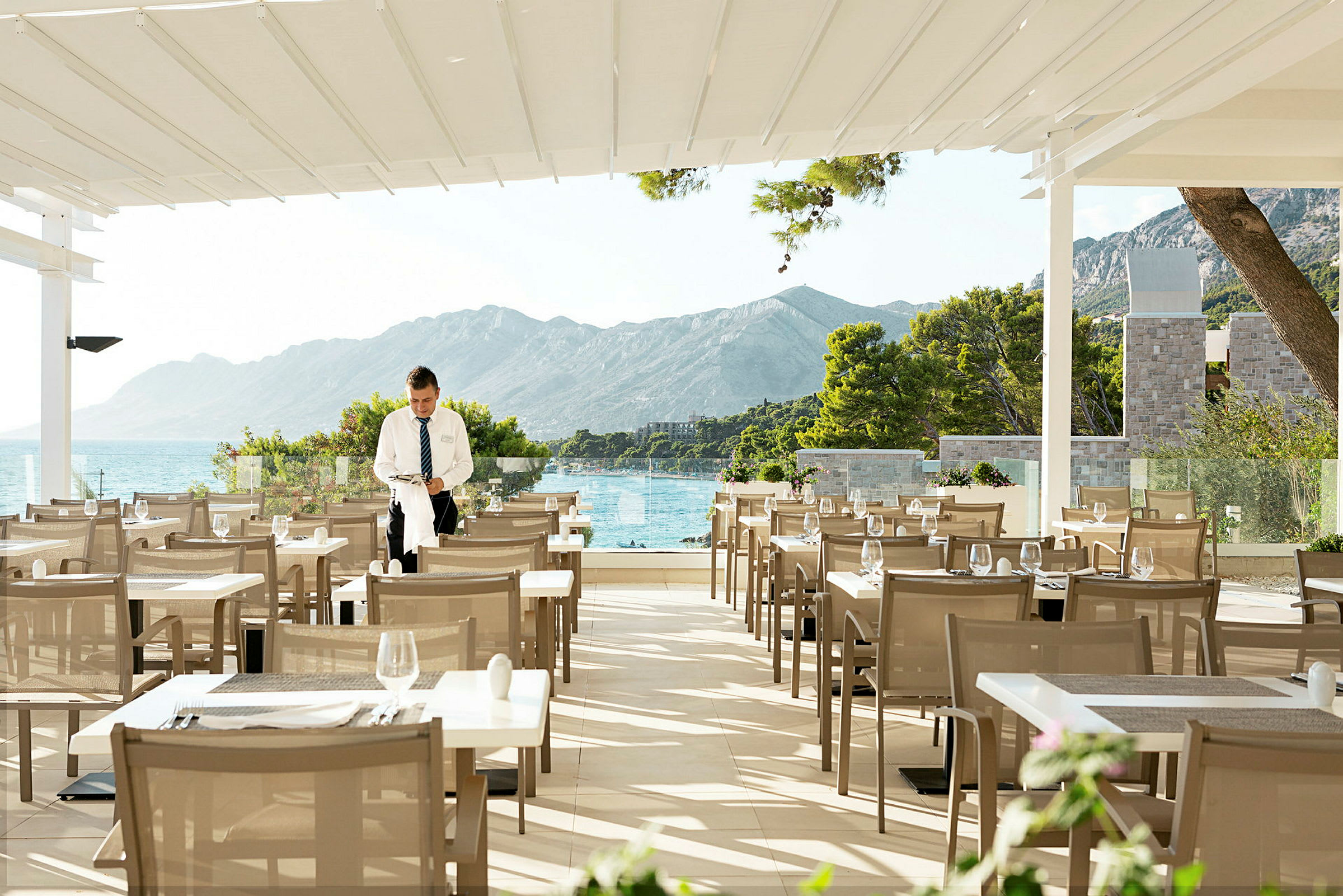 Restaurangterrass med utsikt över havet och berg. (AI-genererad text)