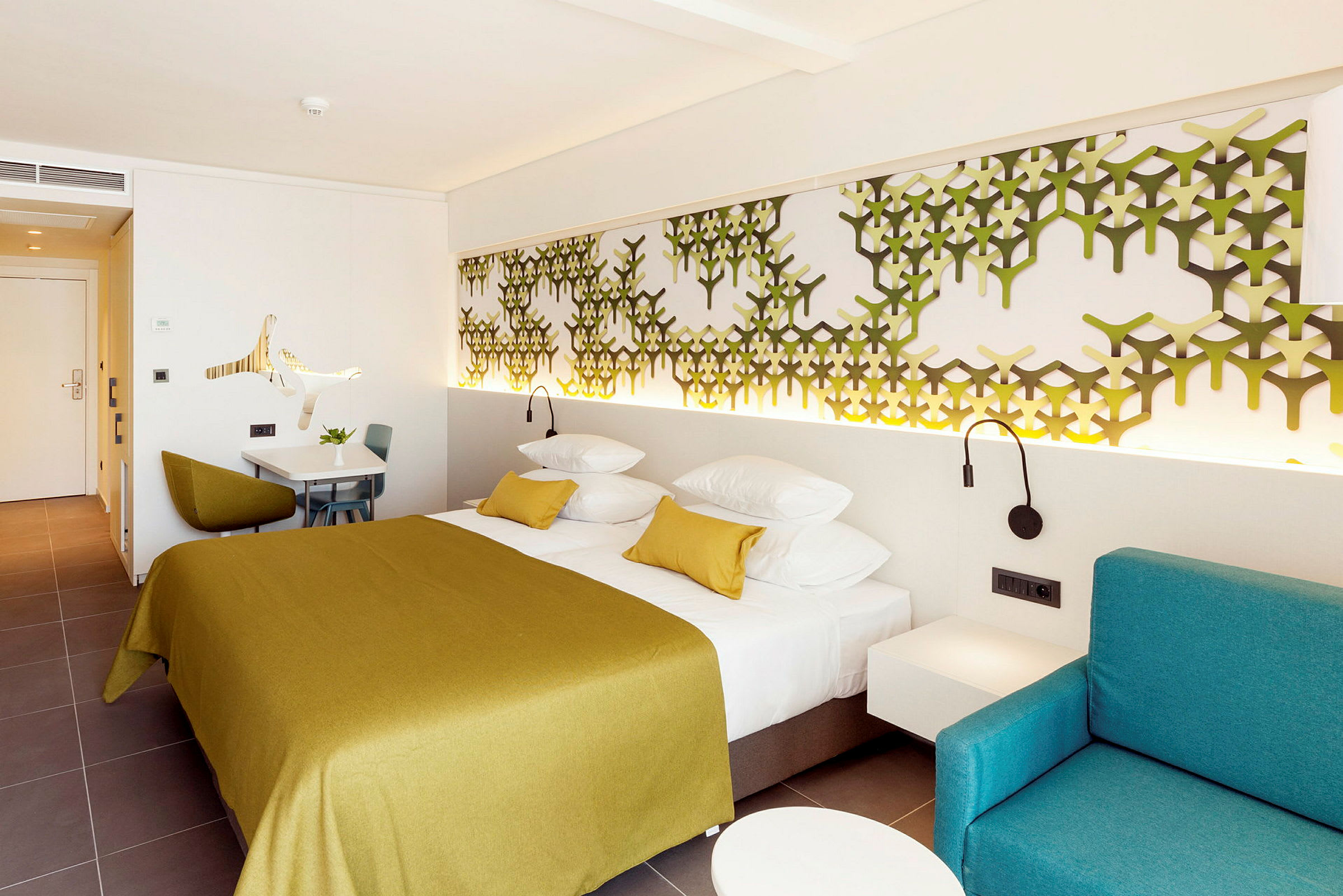 Ett modernt hotellrum med en dubbelsäng, väggdekoration och en sittgrupp. (AI-genererad text)