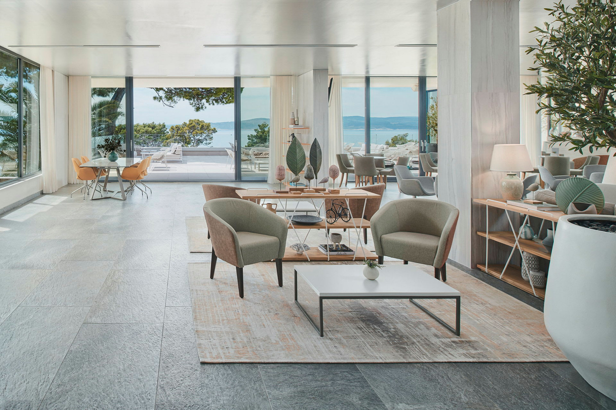 Ett elegant hotellrum med sittgrupp, stora fönster och utsikt mot havet. (AI-genererad text)