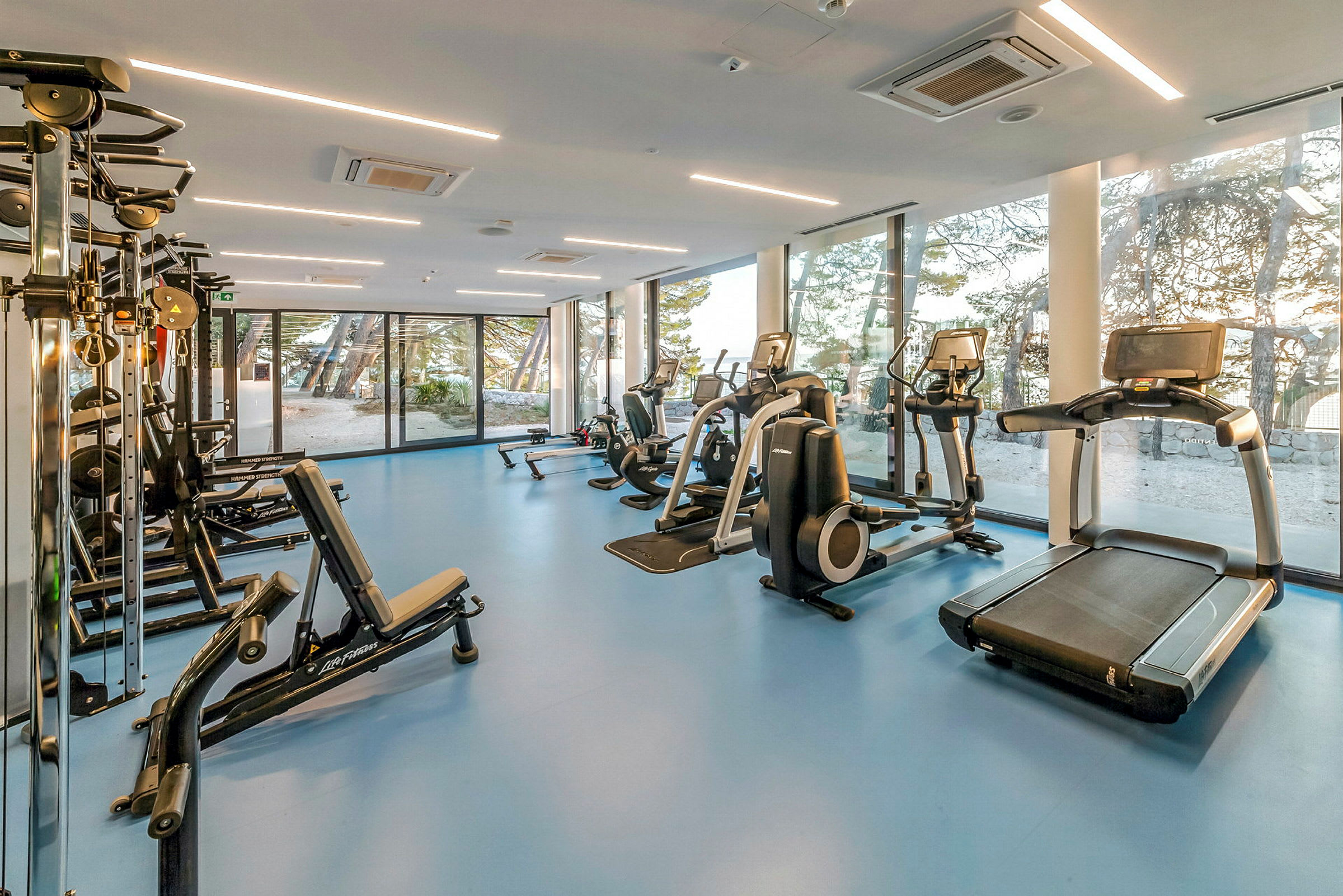 Gym med träningsmaskiner och stora fönster. (AI-genererad text)