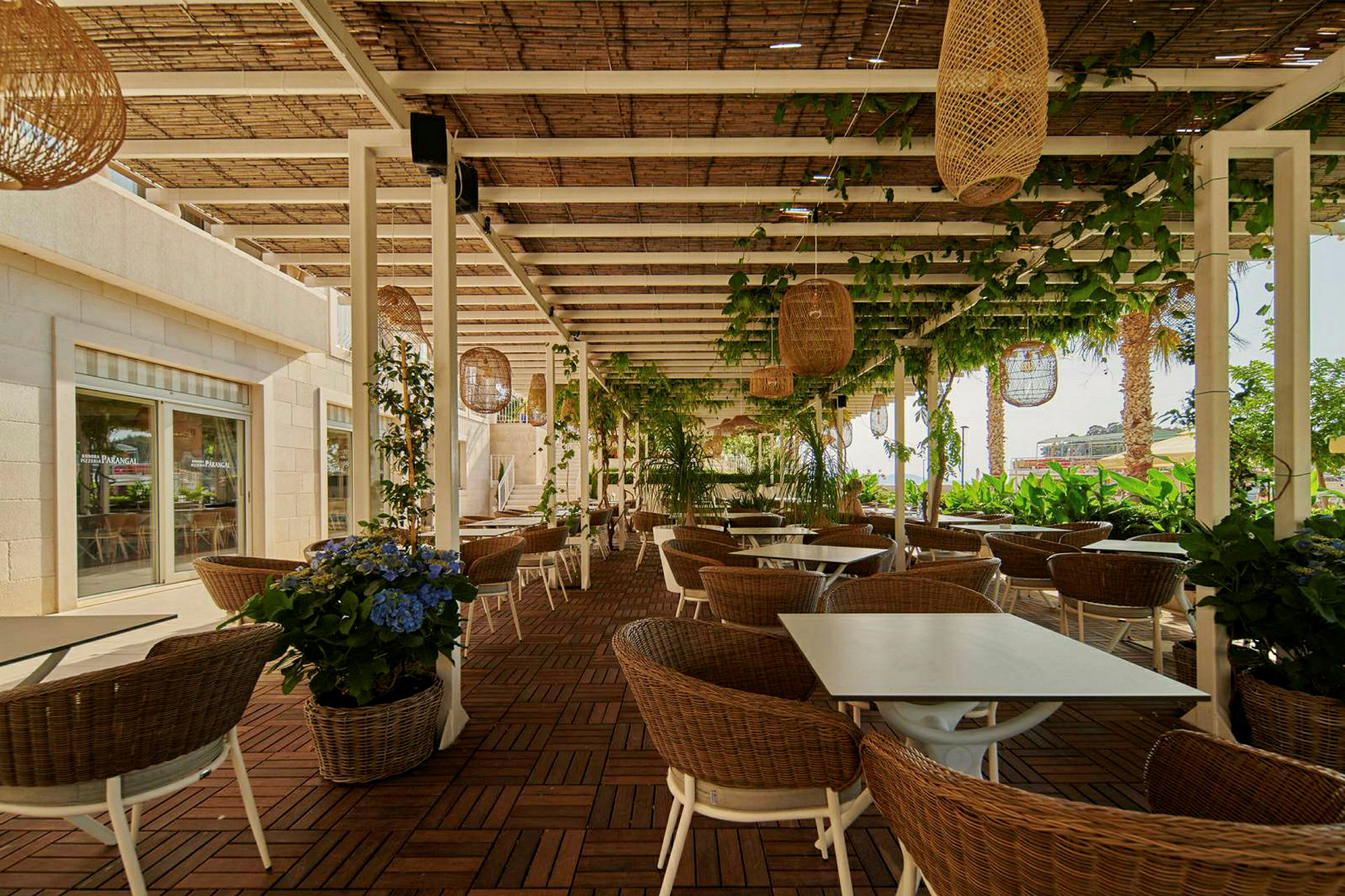 Uteservering med bord, stolar och växter under en pergola. (AI-genererad text)