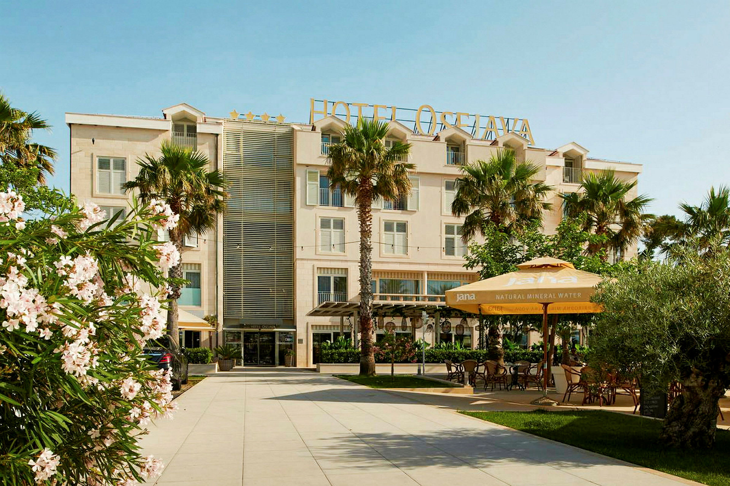 Hotellbyggnad med entré, omgiven av palmer och blommor. (AI-genererad text)