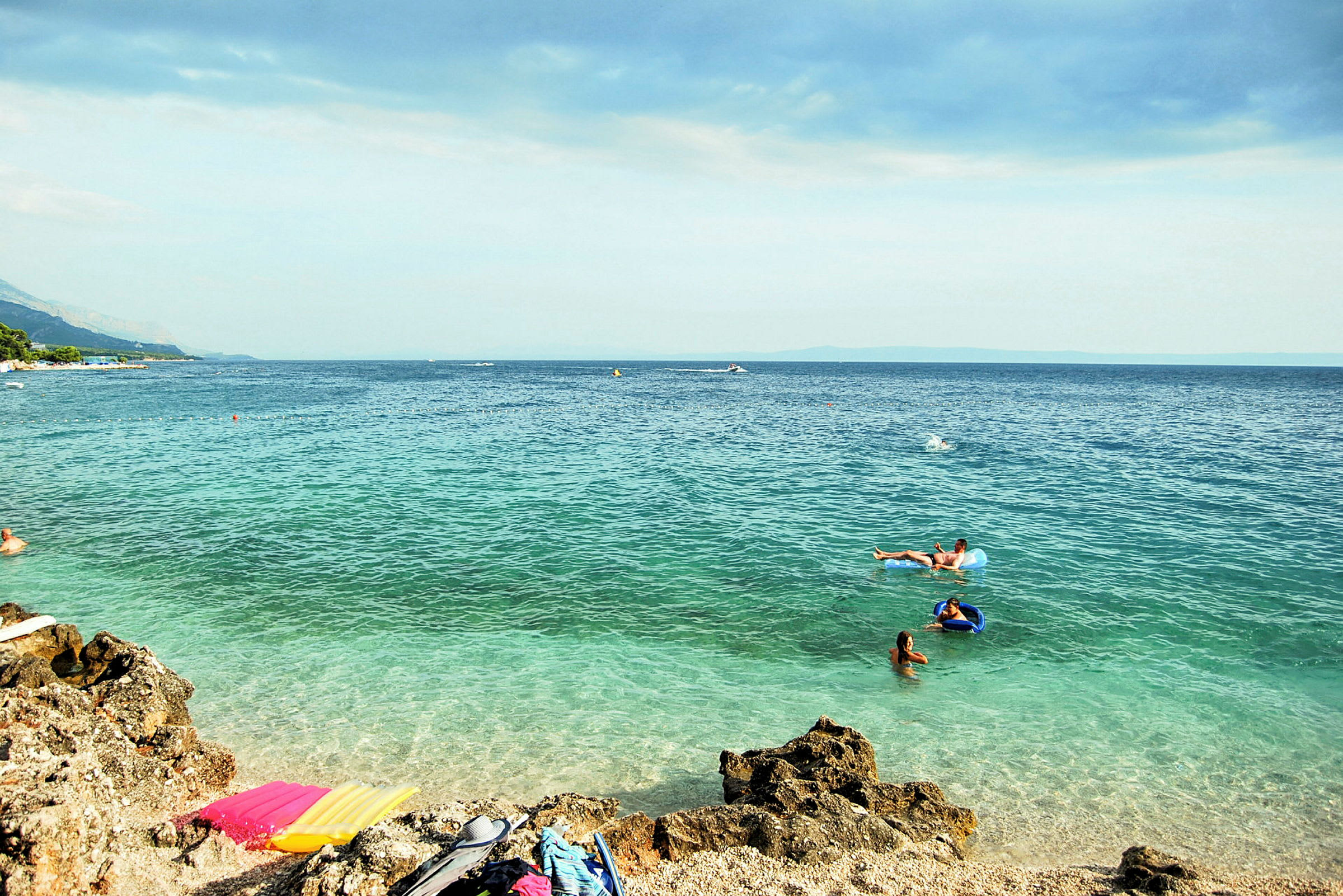 Strand med människor som badar i havet. (AI-genererad text)